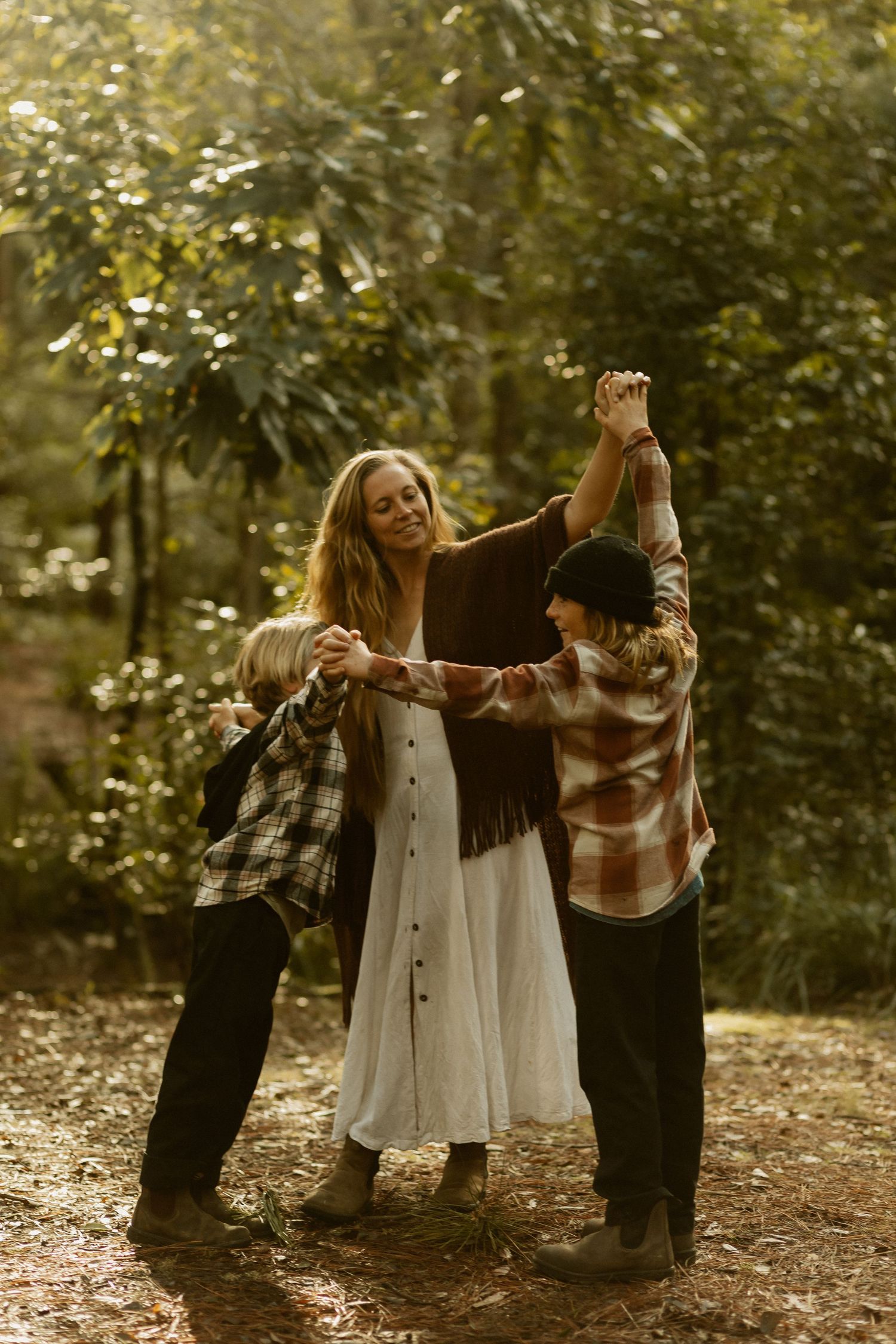 A joyful outdoor gathering in golden sunlight with people in casual autumn attire dancing together in the woods.
