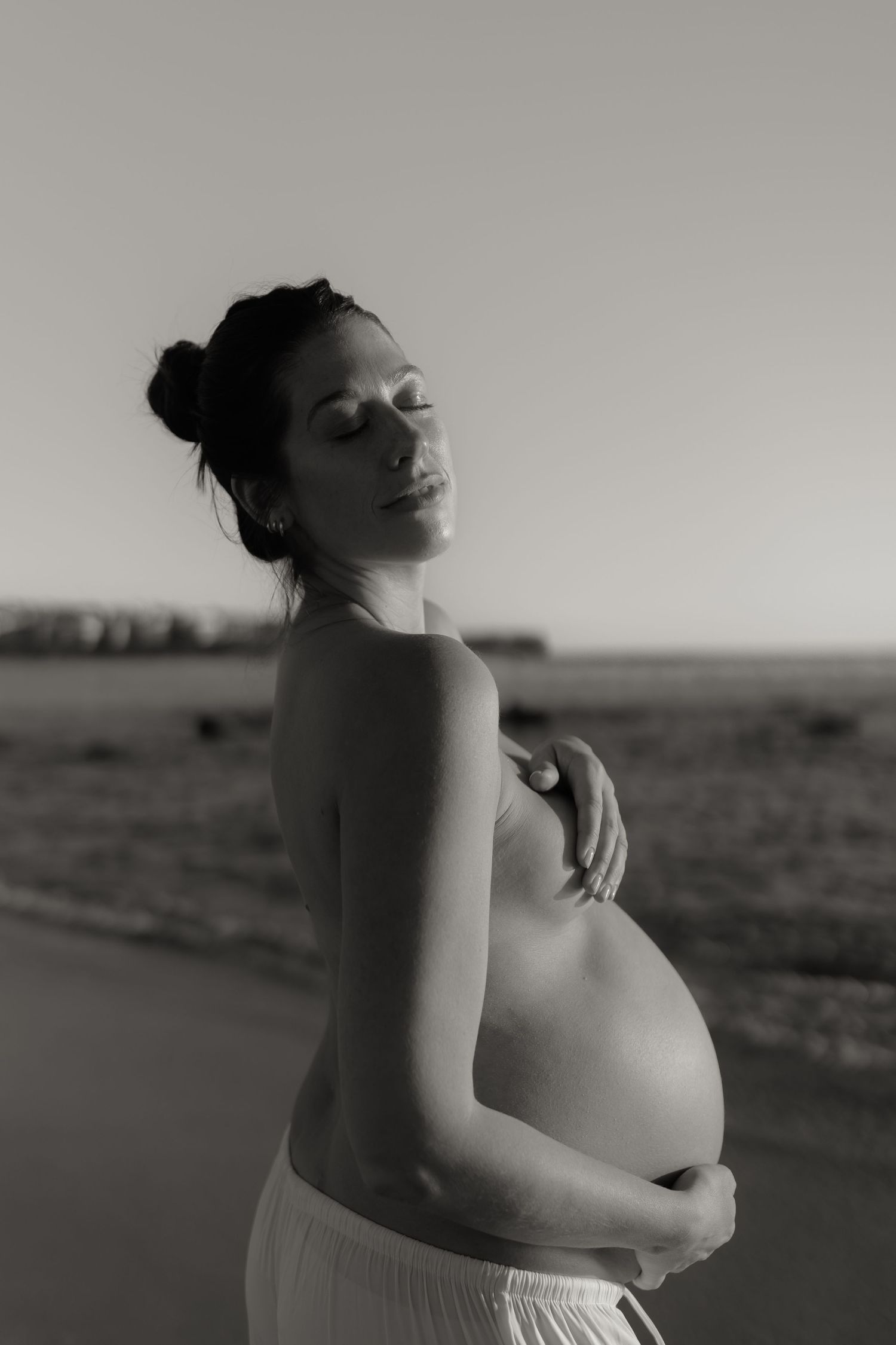A silhouetted maternity photoshoot on the beach in black and white.