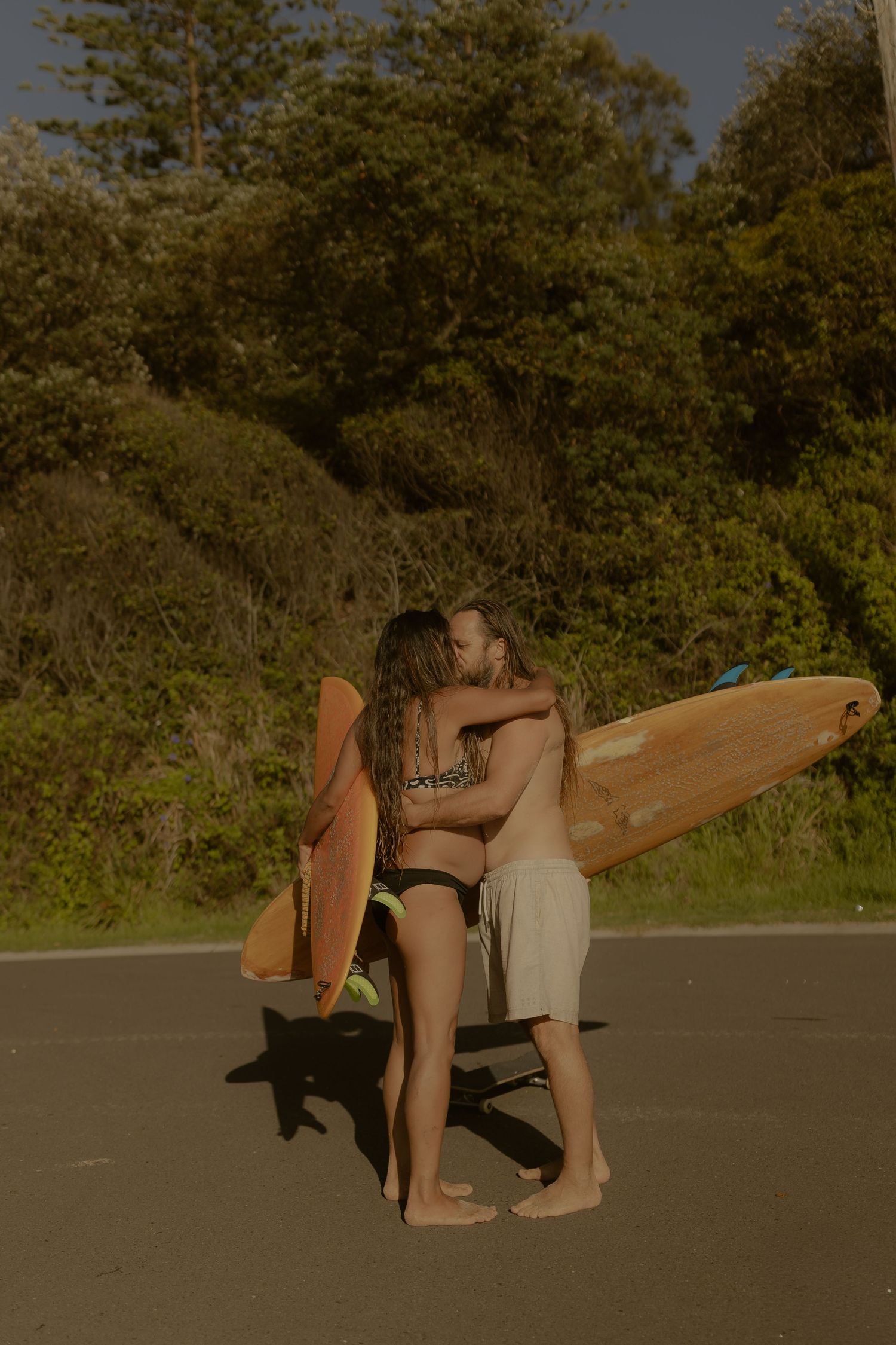 Two friends with surfboards sharing a moment in golden afternoon light.