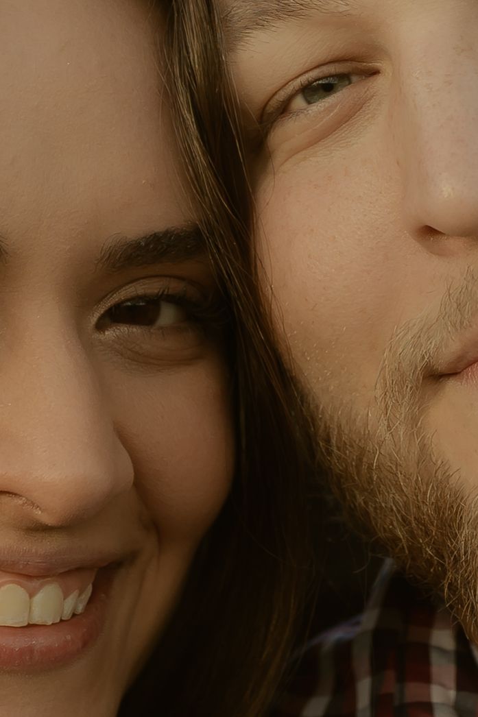 Close-up portrait of a smiling young woman and bearded man with faces pressed together cheek to cheek.