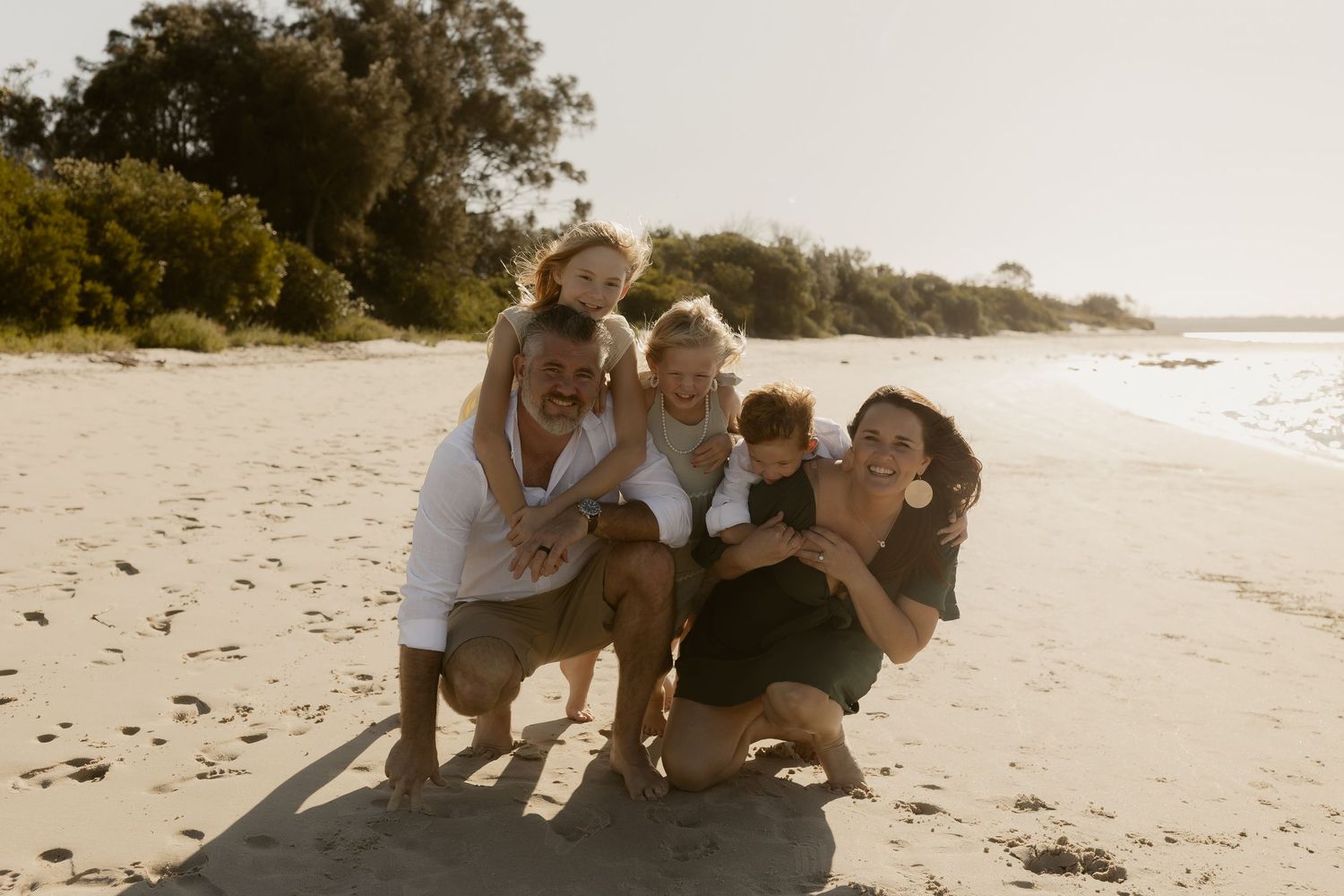 Playful beach photoshoot sequence showing family members interacting on the sandy shore.