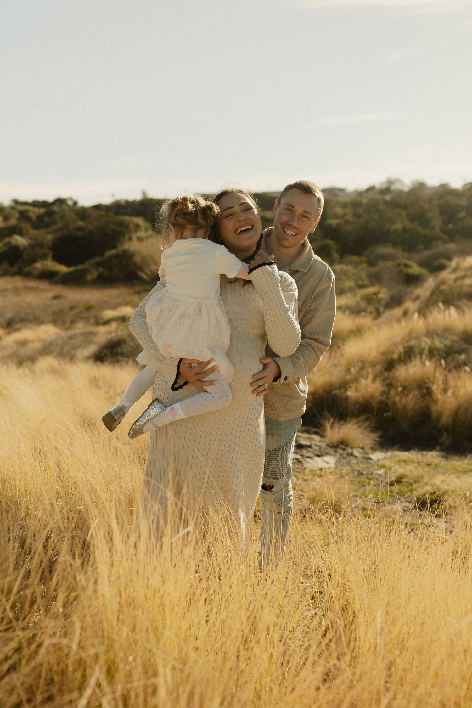 A joyful family embracing together in a golden field during sunset.