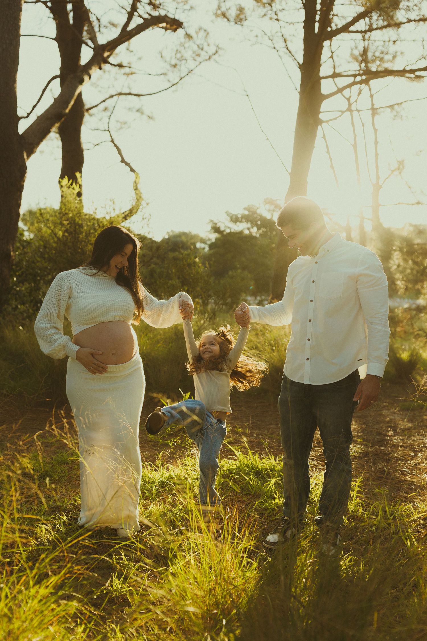 Two people walking hand in hand through tall grass at golden hour.