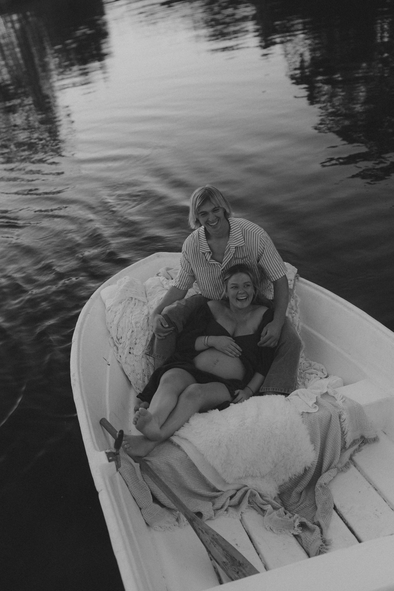 People laughing together while relaxing in a small white boat on calm waters.