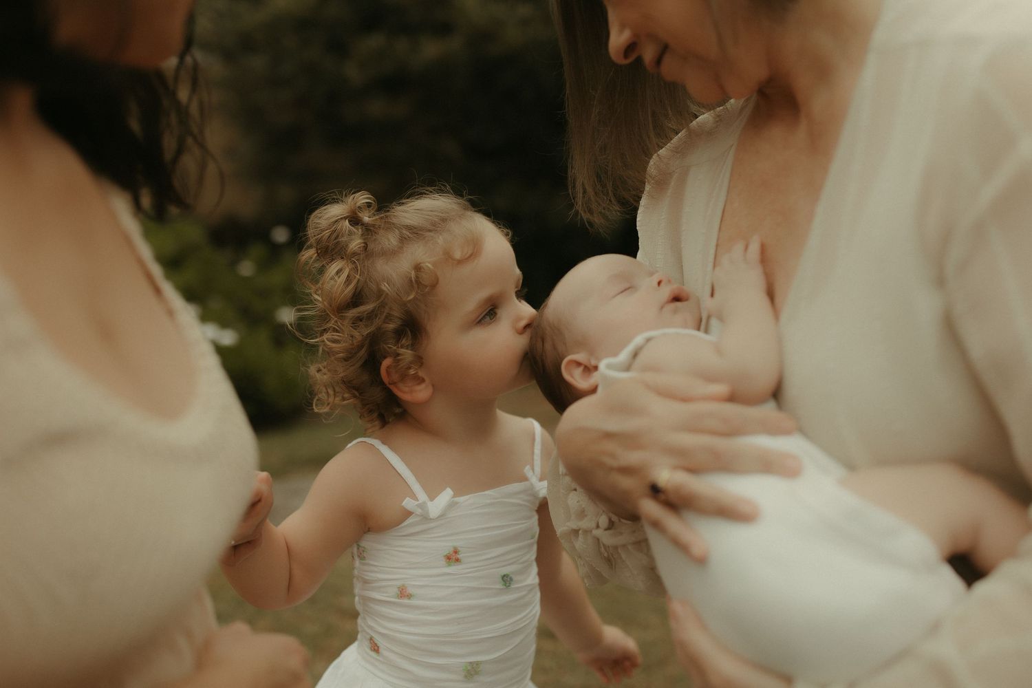 Intimate family moment captured in soft natural lighting with white clothing.