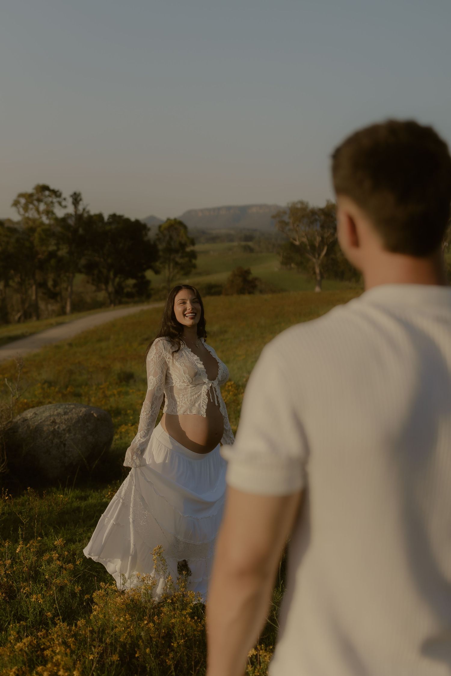 Two figures share a joyful moment in a sunlit meadow filled with yellow wildflowers.
