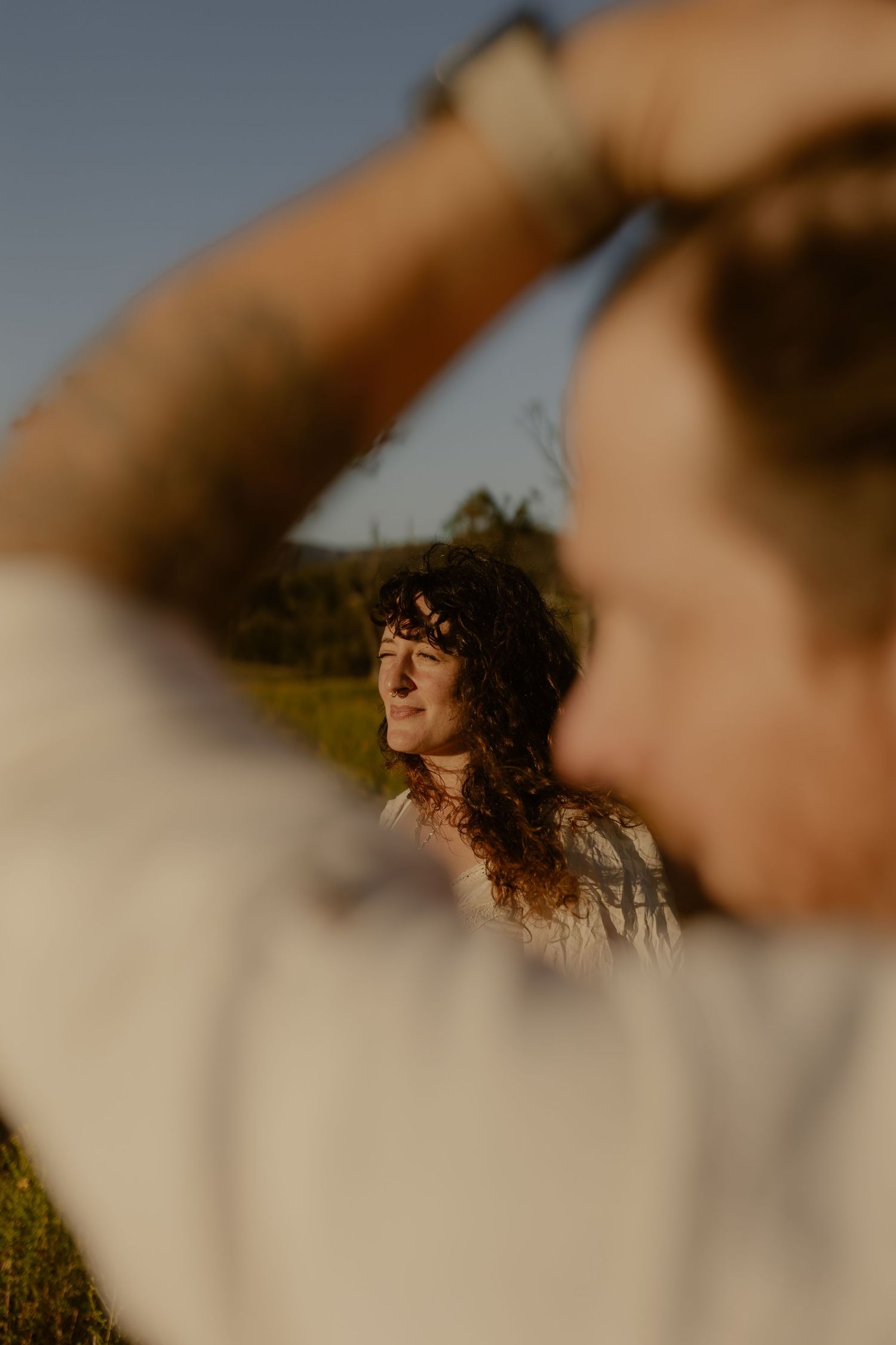 Artistic portrait through golden sunlight in a natural meadow setting.