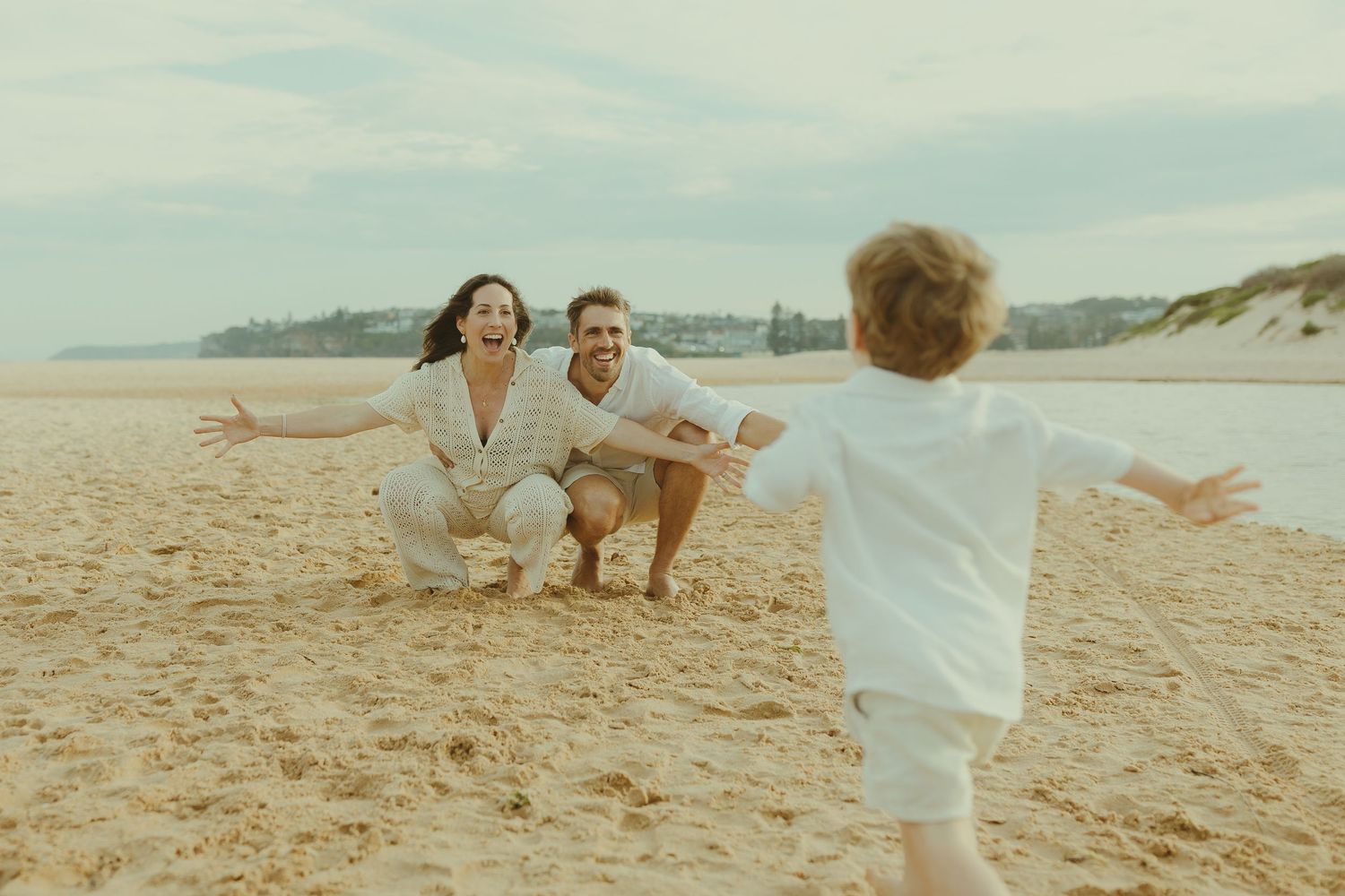Candid family beach photoshoot with joyful interactions in warm sunlight.