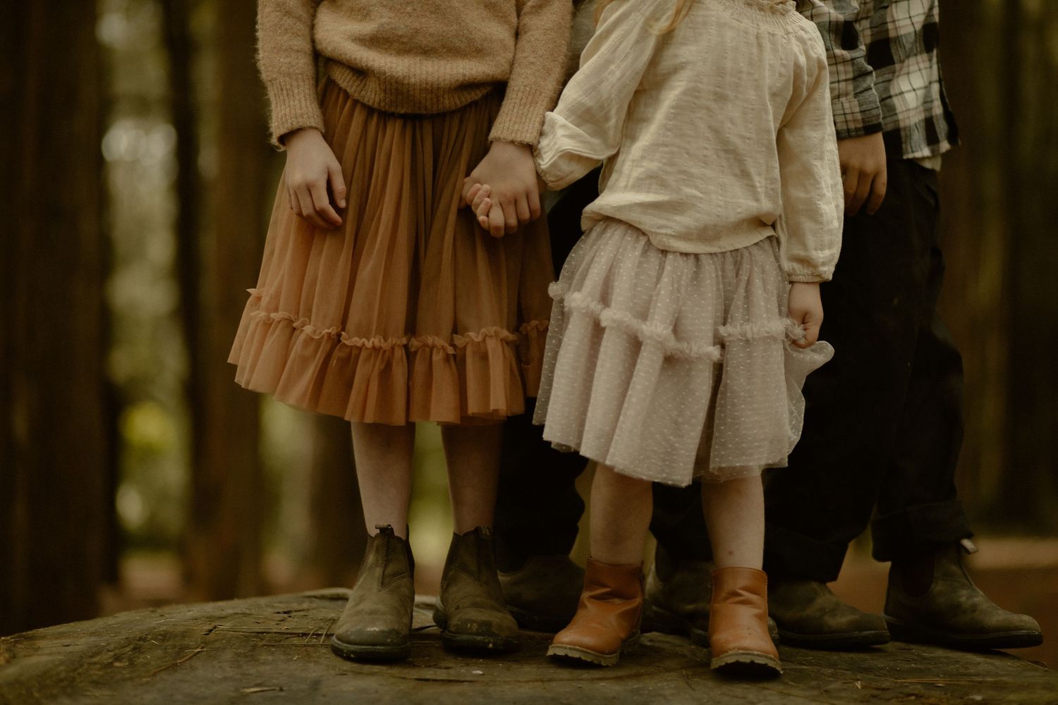 Candid moment of family members standing together on fallen leaves in a forest.