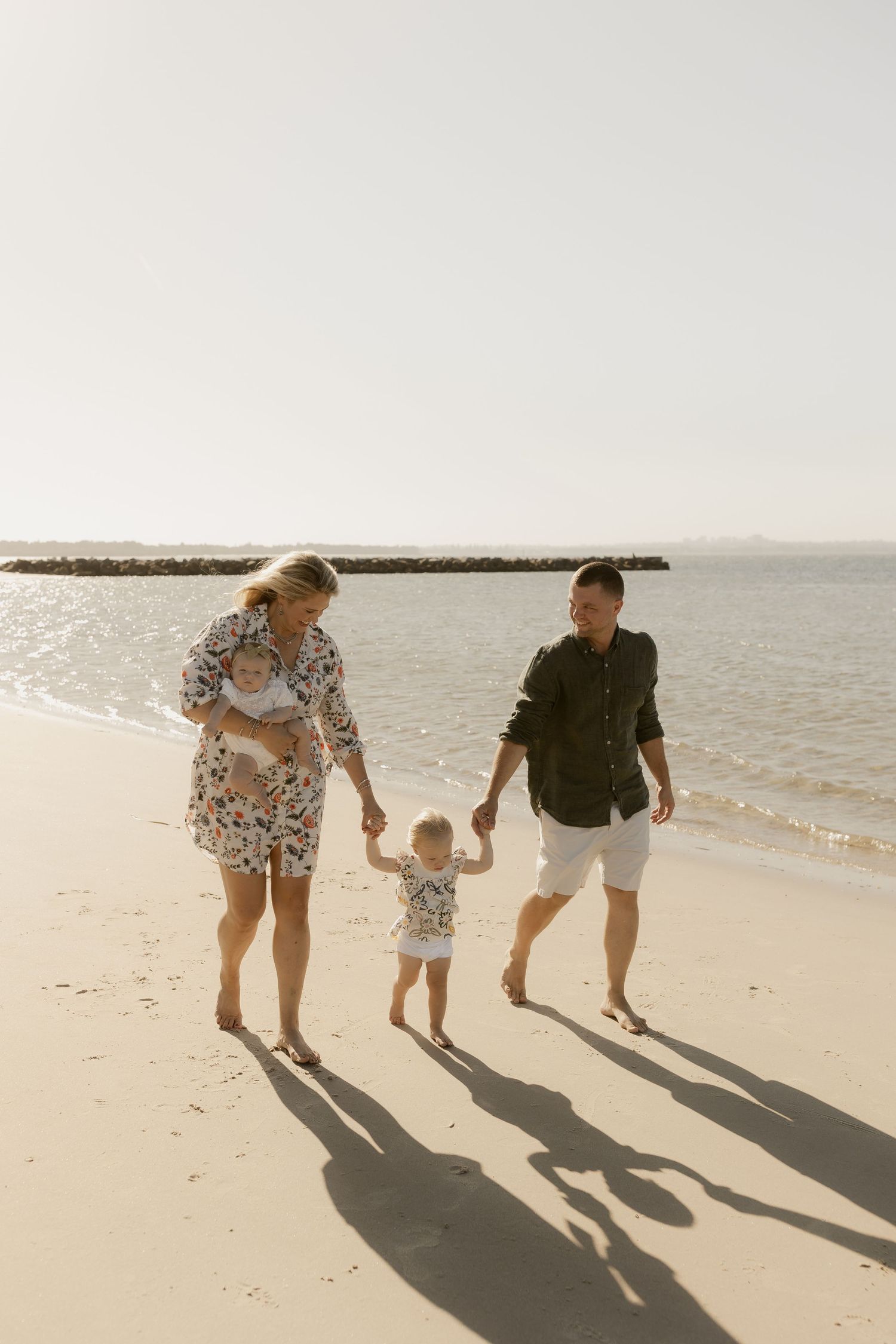 Family walking sequence photos on a beach with long shadows cast in the sand.