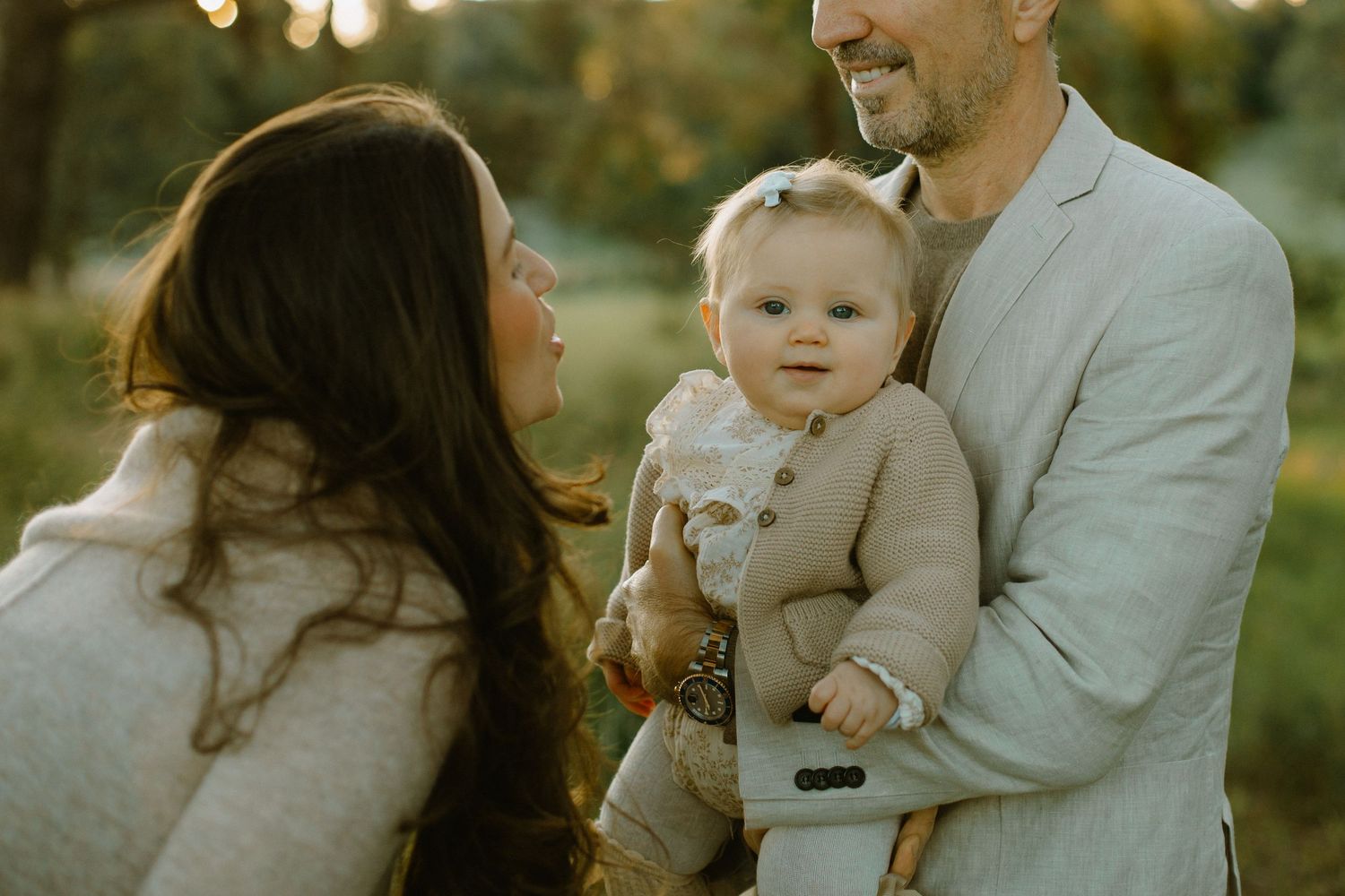Family shares intimate moment outdoors during golden hour portrait session.