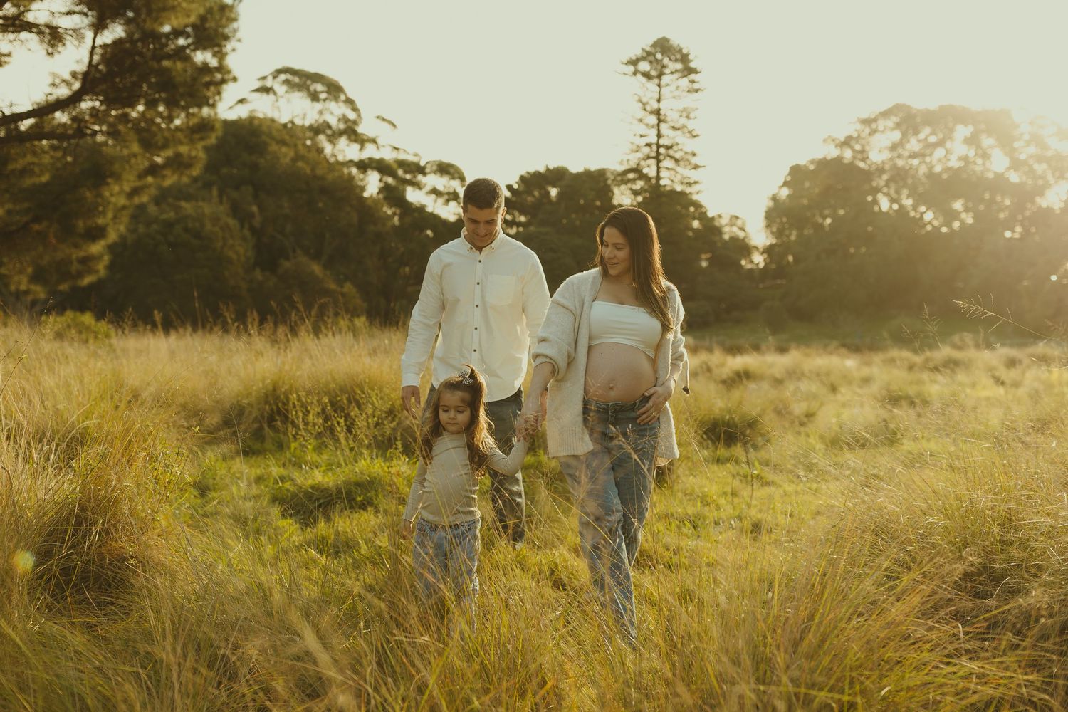 Couple walking together through a serene meadow landscape at sunset.