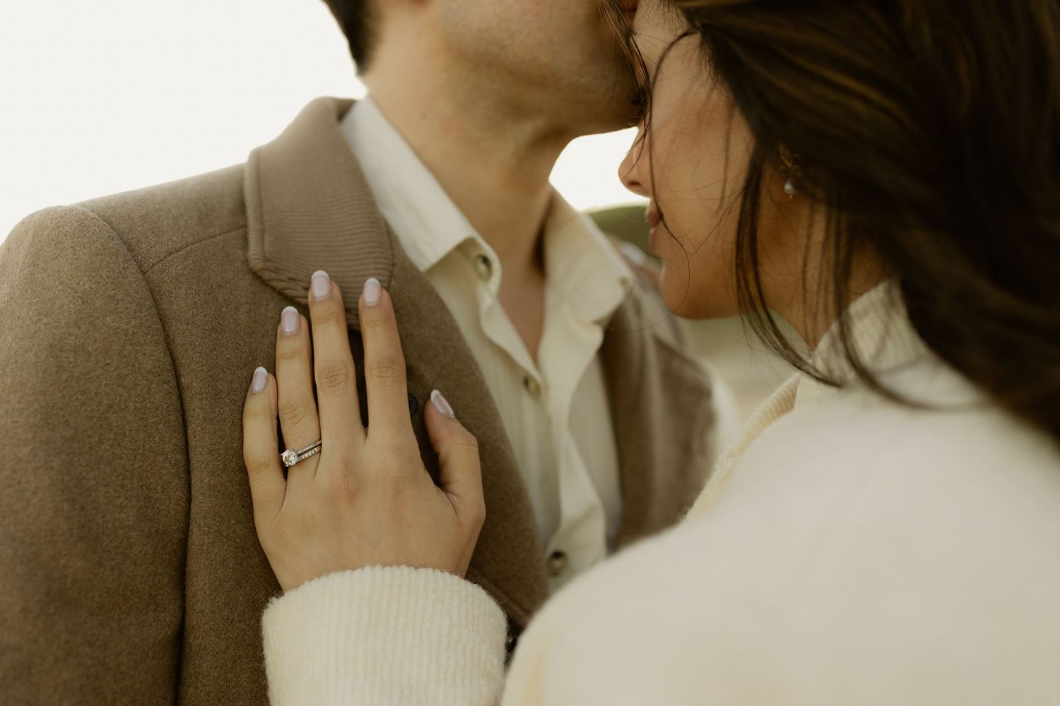 Close-up of couple almost kissing, woman's hand on man's chest showing diamond engagement ring.