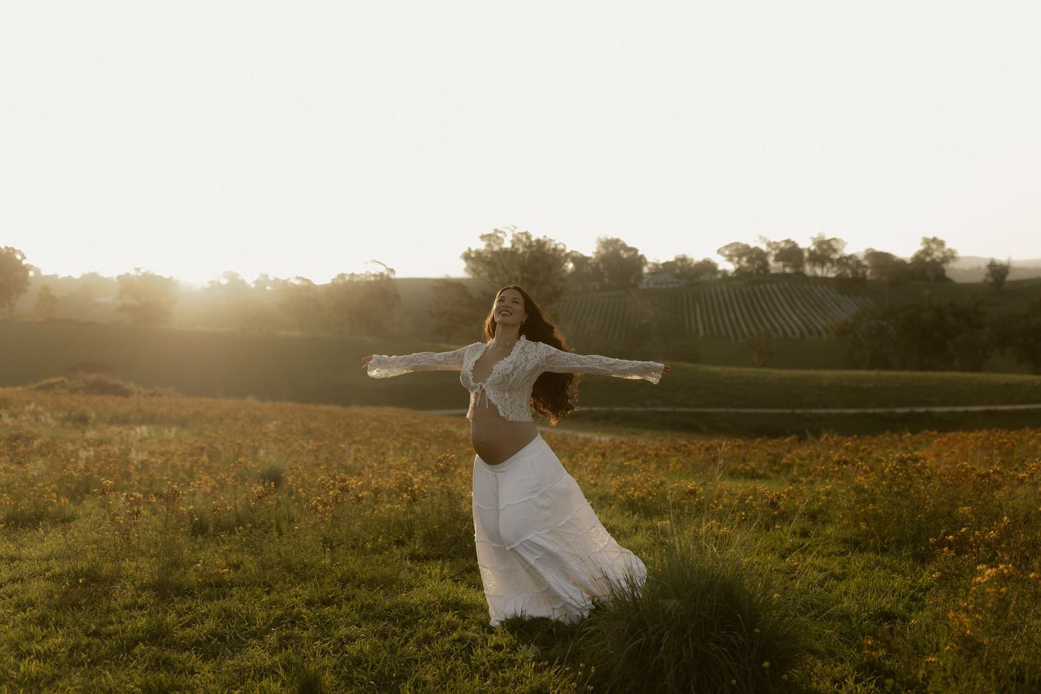 A dreamy sunset photoshoot in a vast field with mountains in the background.