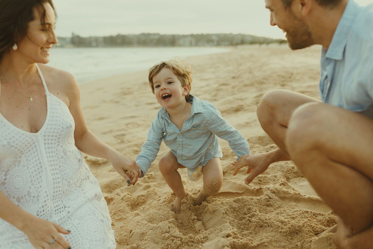 Family enjoying candid moments together during golden hour beach photography session.