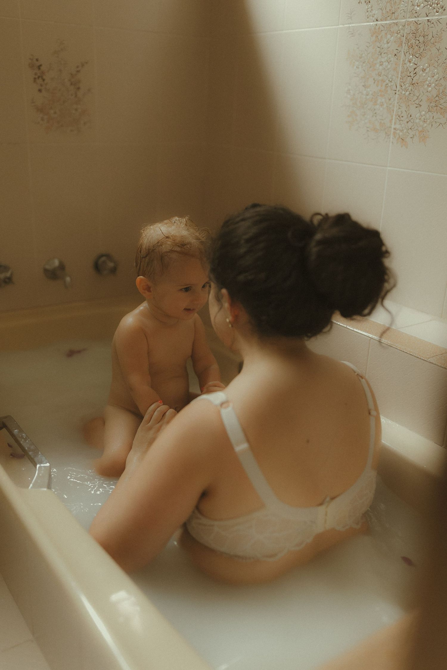 Candid bathroom scene showing intimate bonding time between parent and child.