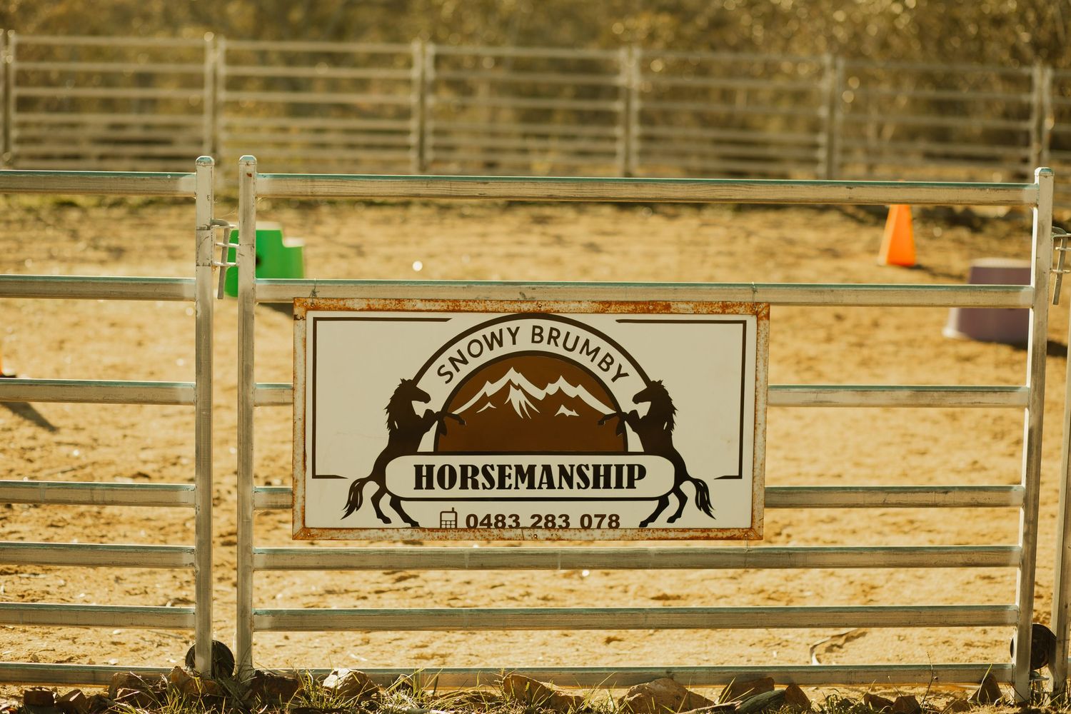 A wooden sign displays 'Horsemanship' text at a rustic ranch fence.