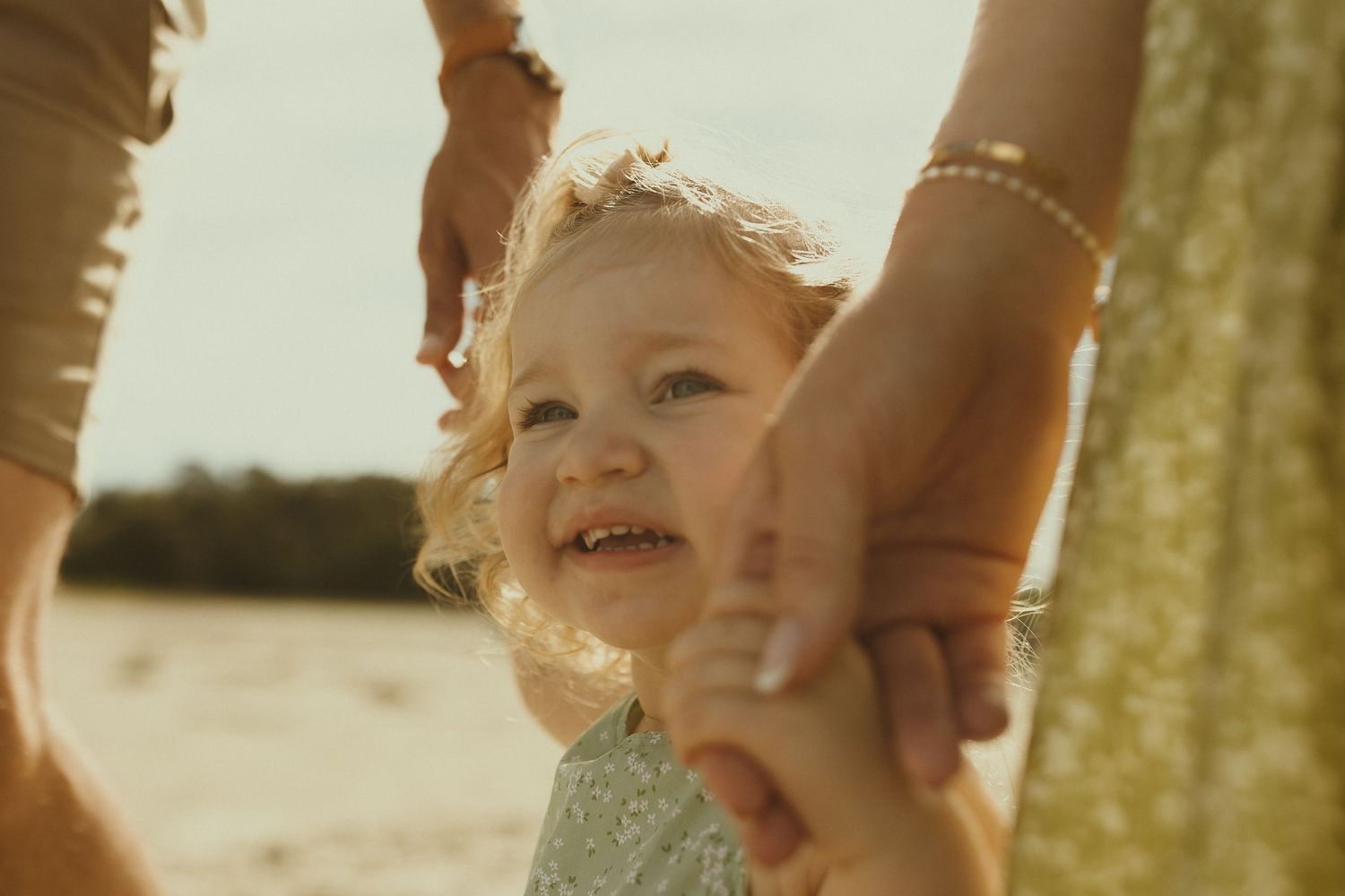 Young child laughs joyfully while playing outdoors in warm golden sunlight.