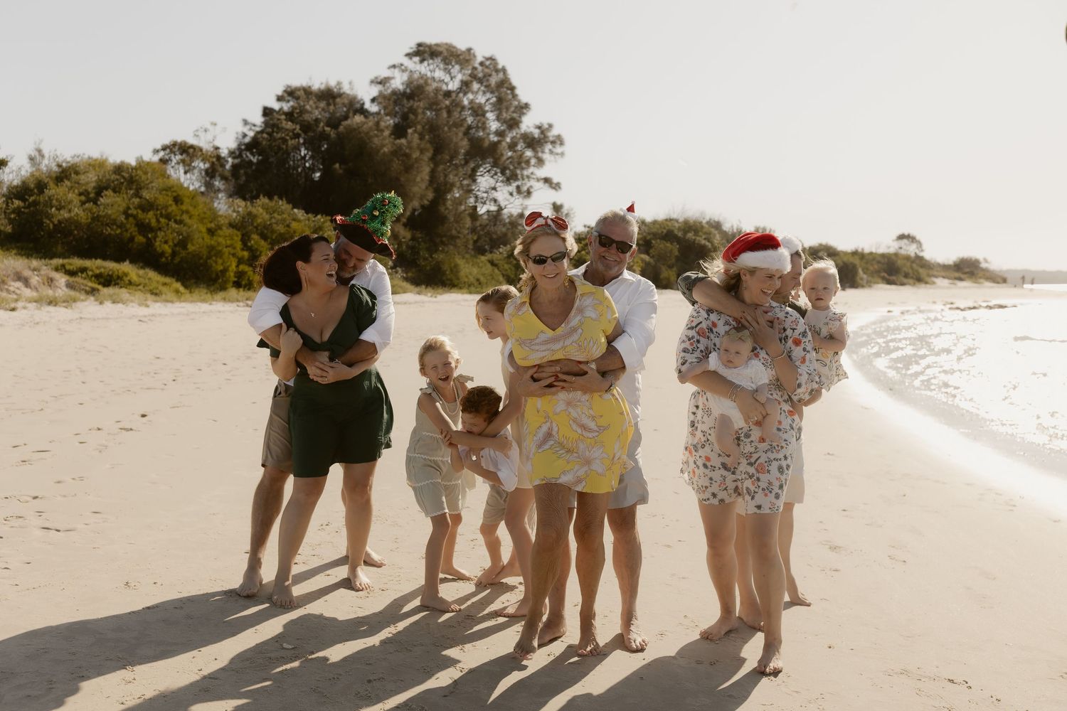 Happy family gathering for photos on a beautiful beach at sunset.