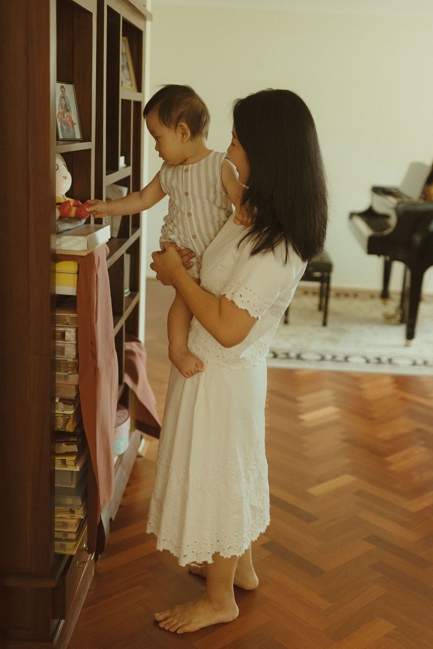 A white lace dress sways as people explore a room with herringbone wood floors.