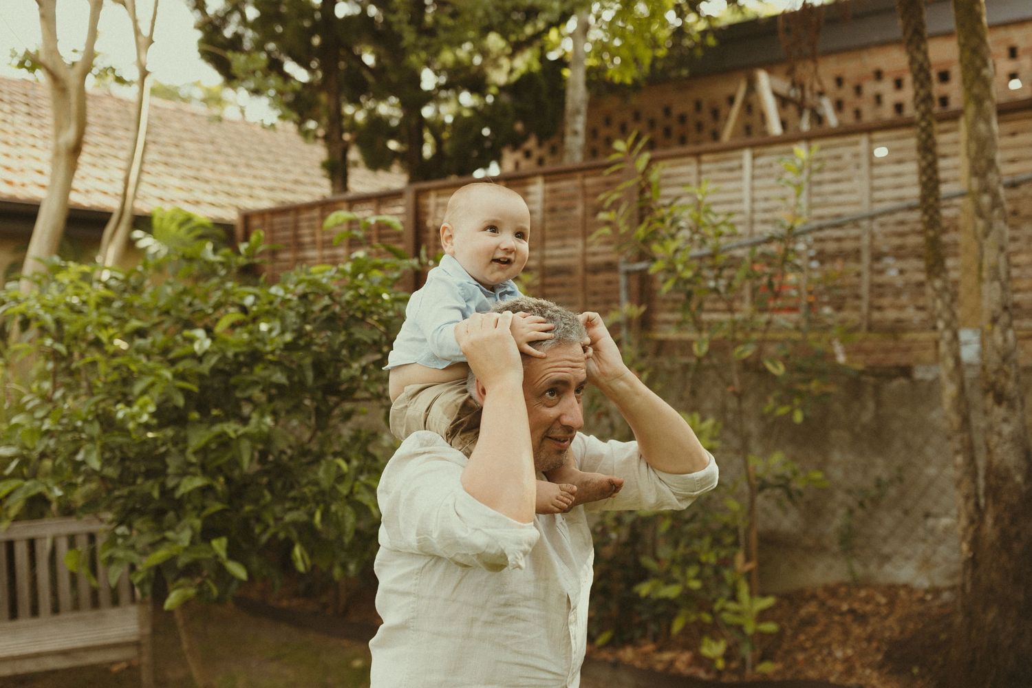 Candid family moments captured in a backyard garden setting with natural lighting.