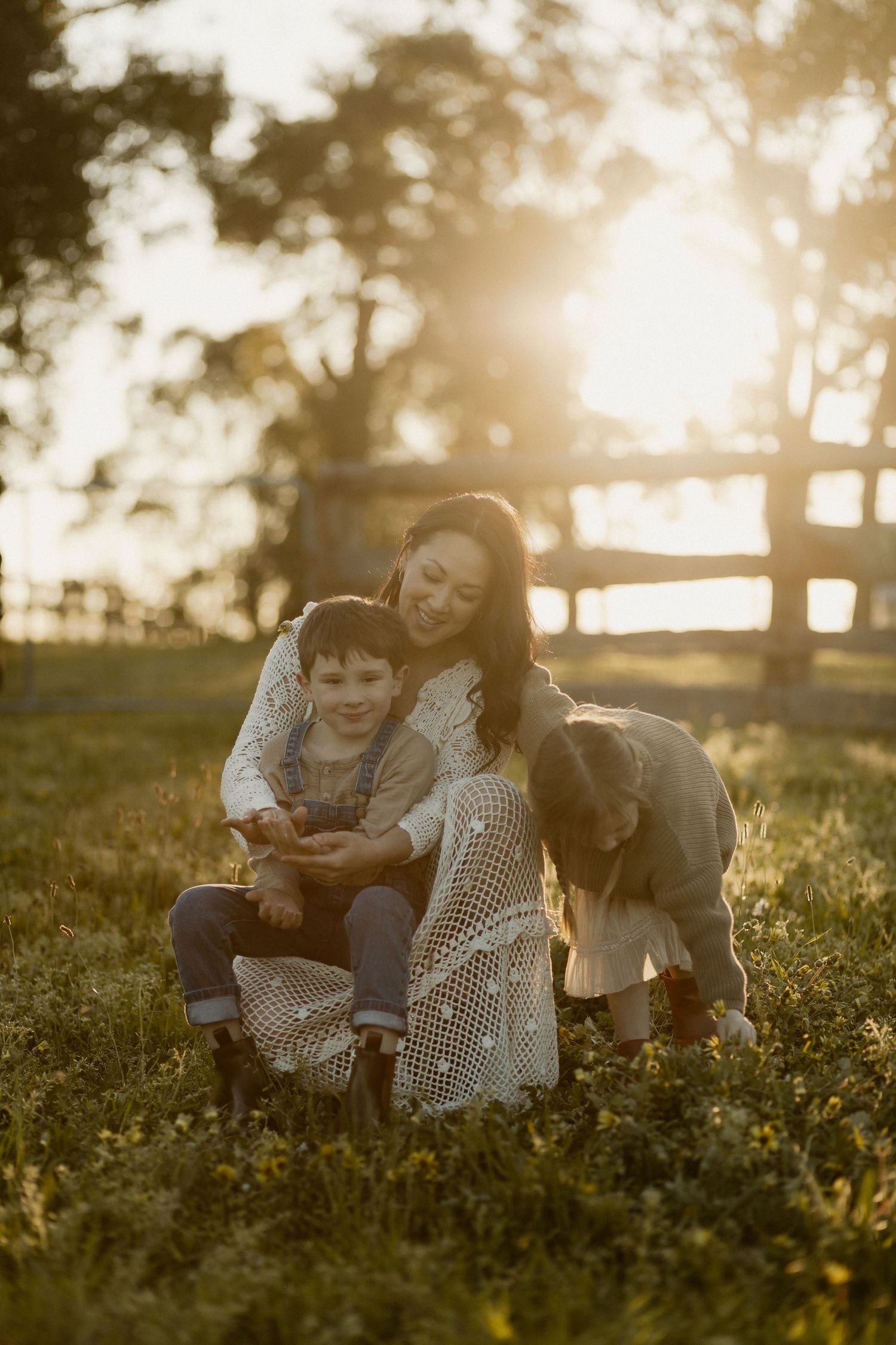 Candid outdoor family photography session in a meadow at sunset with warm golden lighting.