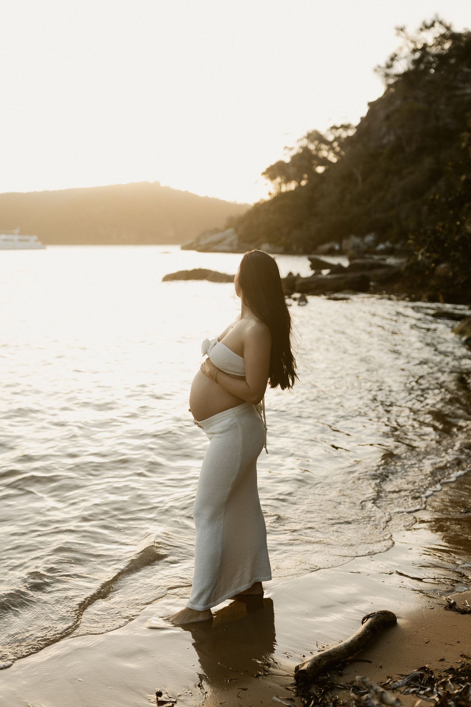 Silhouette captures tender moments of a maternity photoshoot along a serene beach at golden hour.