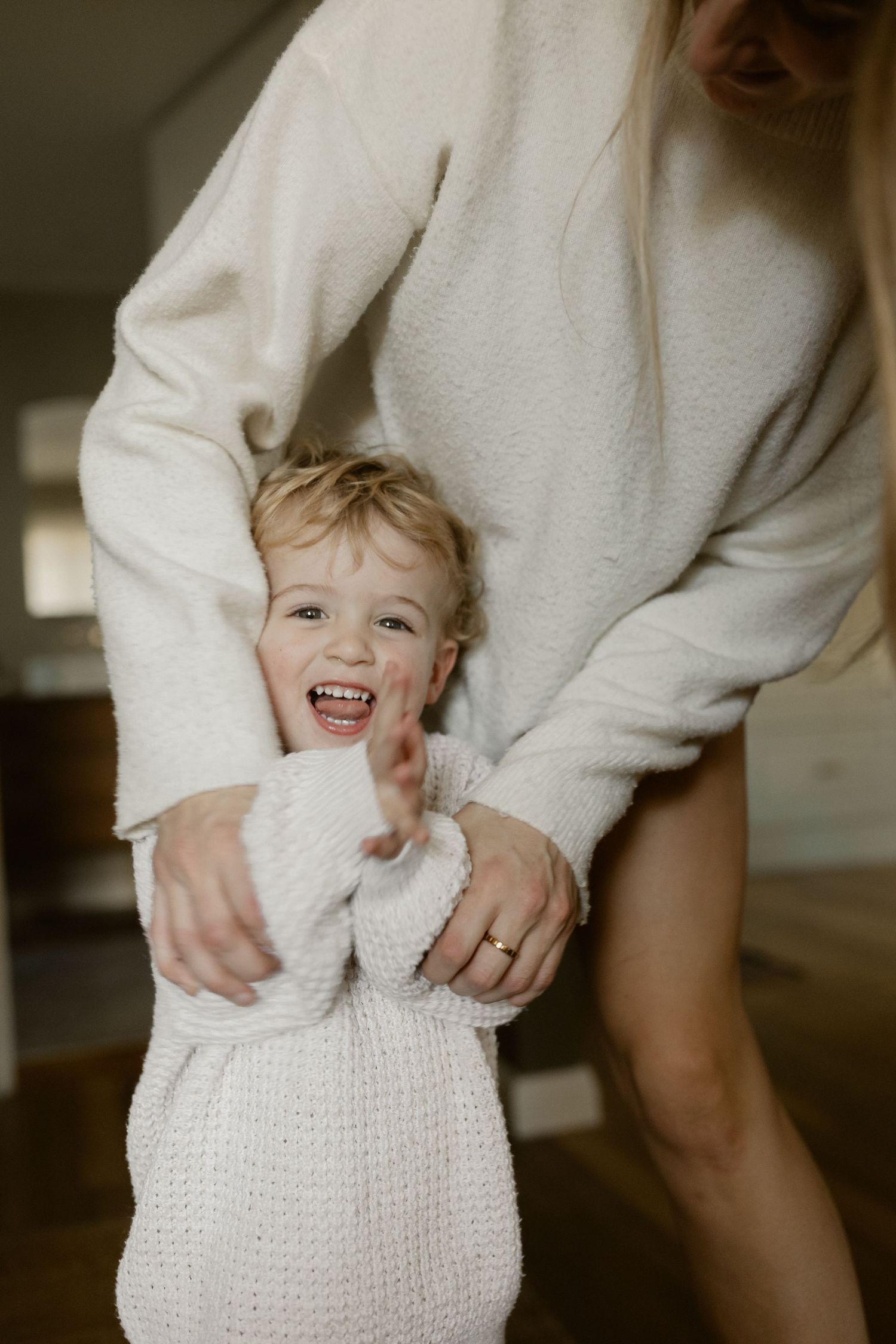 Joyful candid moment of toddler in white sweater playing indoors.