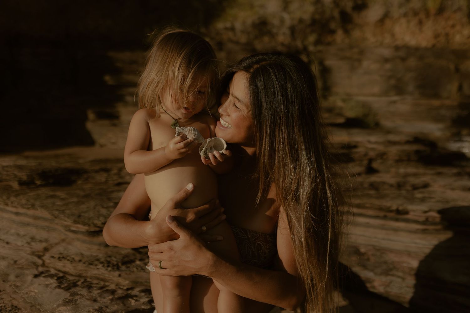 Intimate moment captured on a sandy beach with warm golden light filtering through the scene.