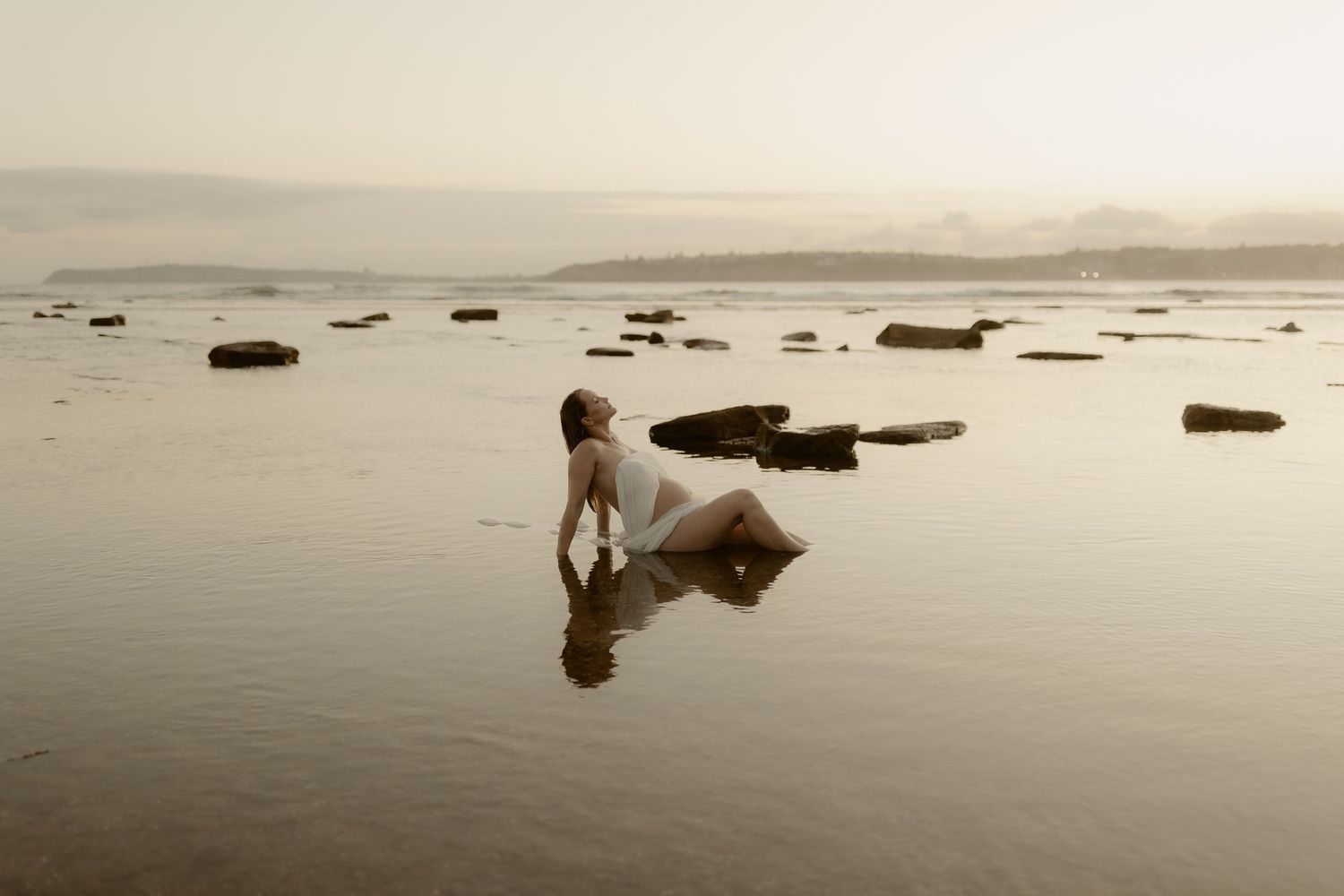 Artistic seascape photograph with rocks scattered across shallow water during low tide.