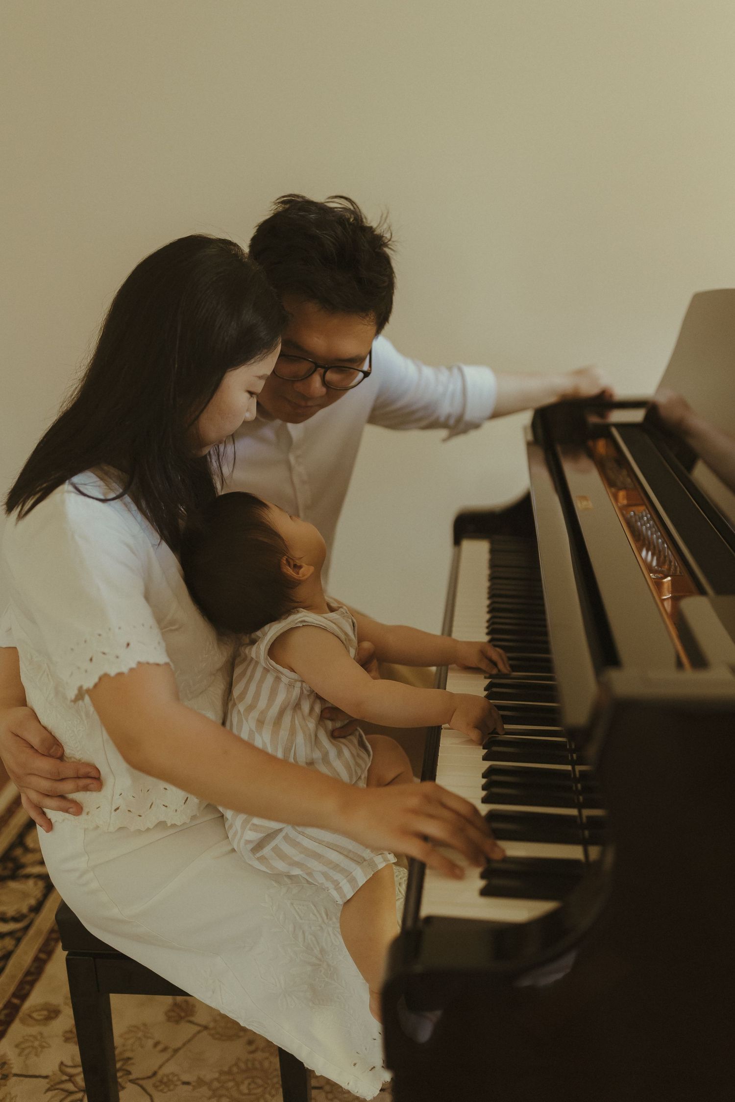 A family shares an intimate moment at the piano as they teach a young child to play.