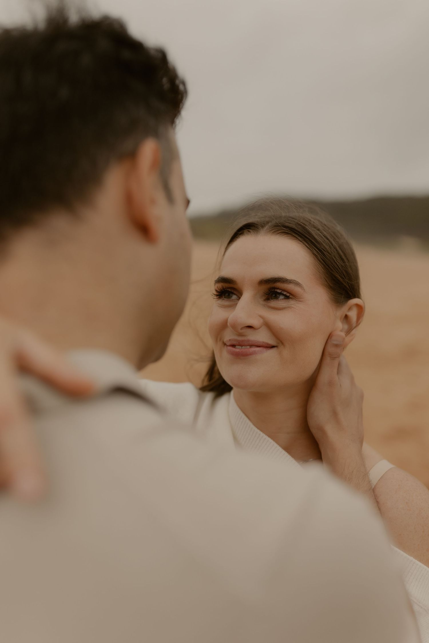 An intimate close-up moment between a couple on a beach during golden hour.