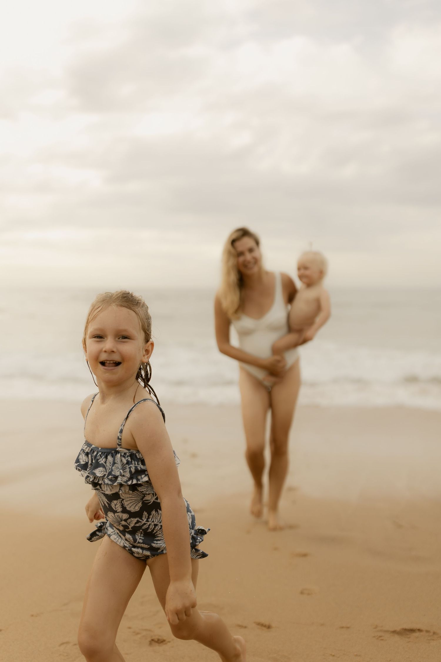 A joyful beach scene with people enjoying a sunny day on the sandy shore with cloudy skies in the background.