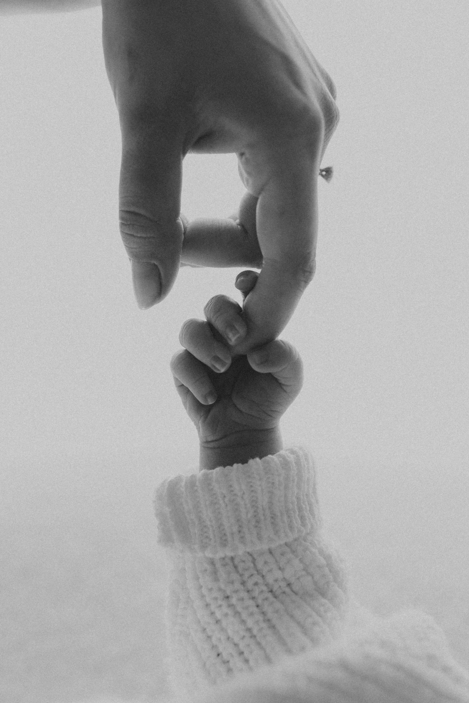 Black and white detail of gentle hand touching soft white knitted fabric.