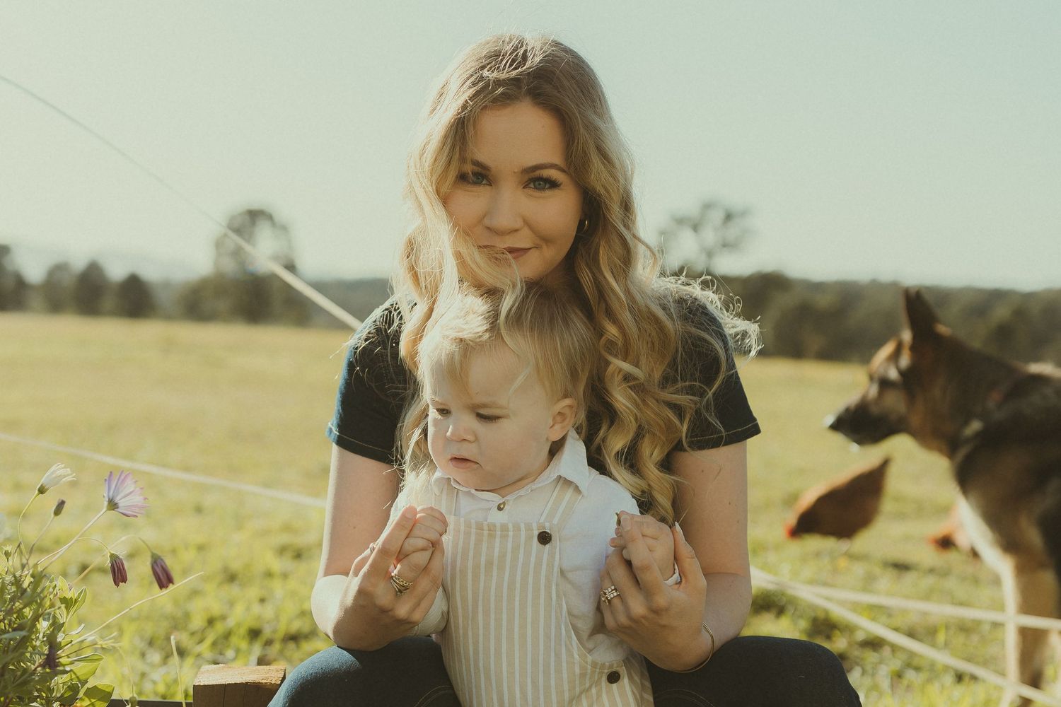 A peaceful moment shared between parent and child outdoors with a dog in the background.