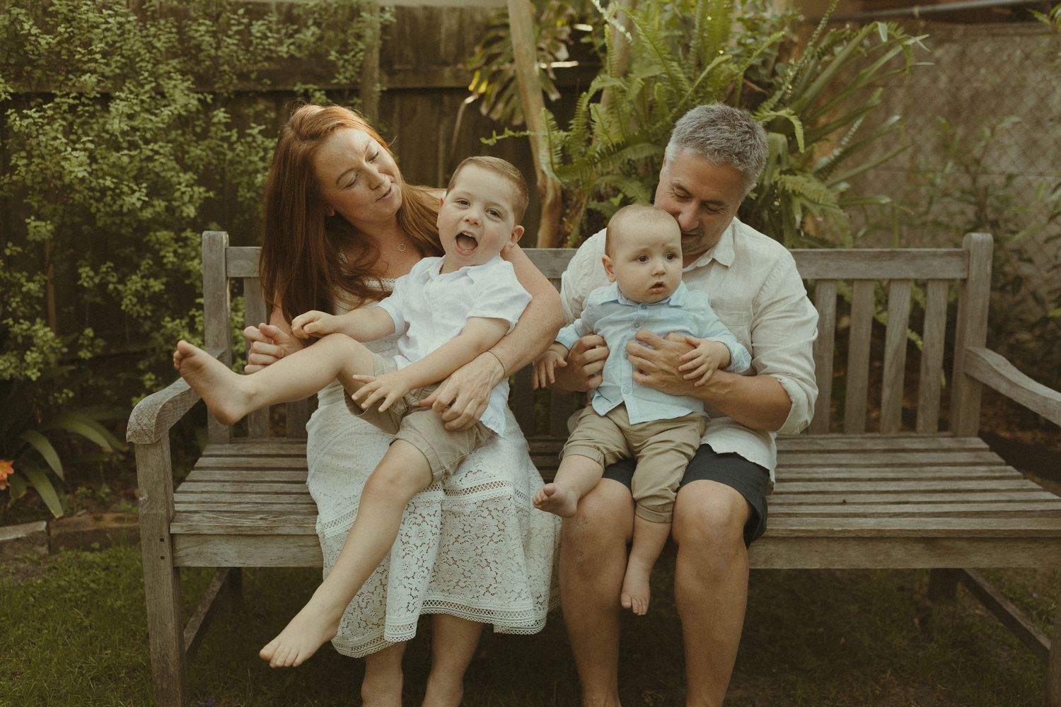 Family enjoying a tender moment together on a wooden garden bench in natural outdoor setting.