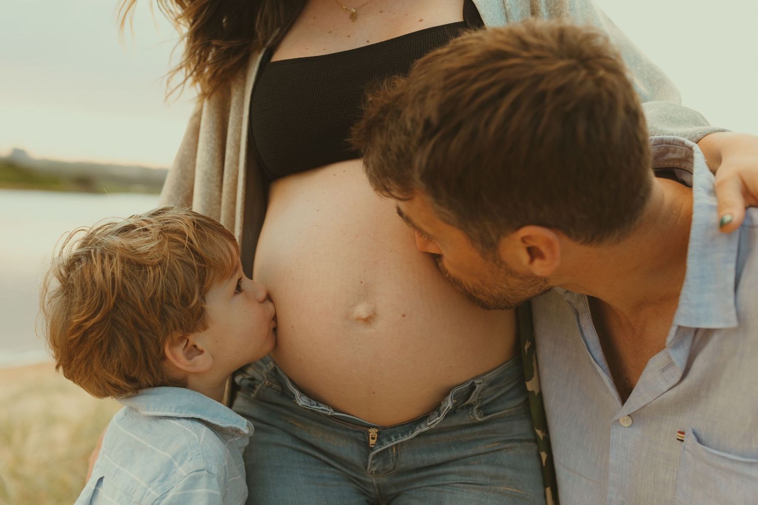 Intimate beach maternity photos capture tender moments between a couple.