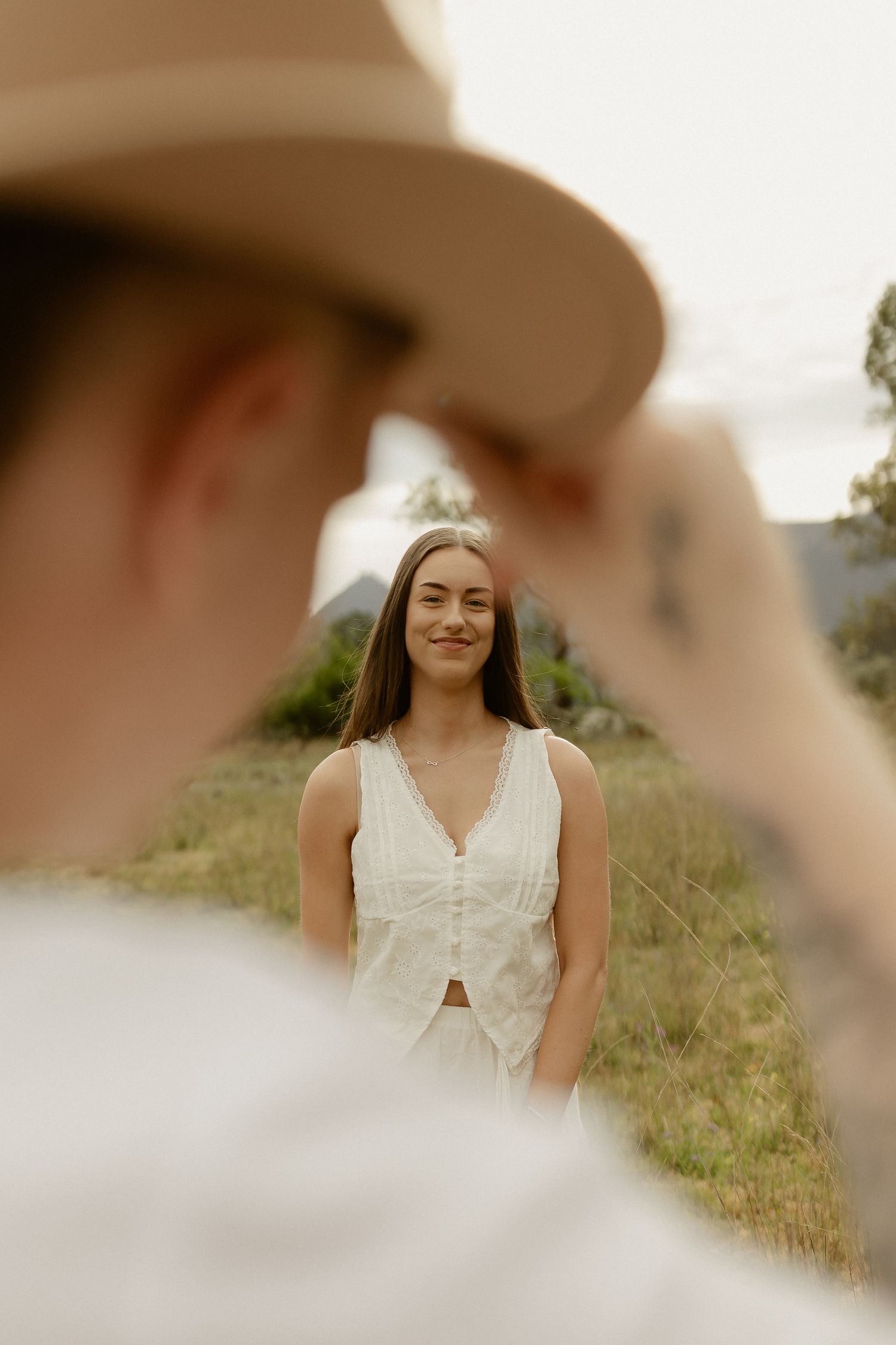 Candid shots through a cowboy hat showing joyful expressions in a natural outdoor setting.