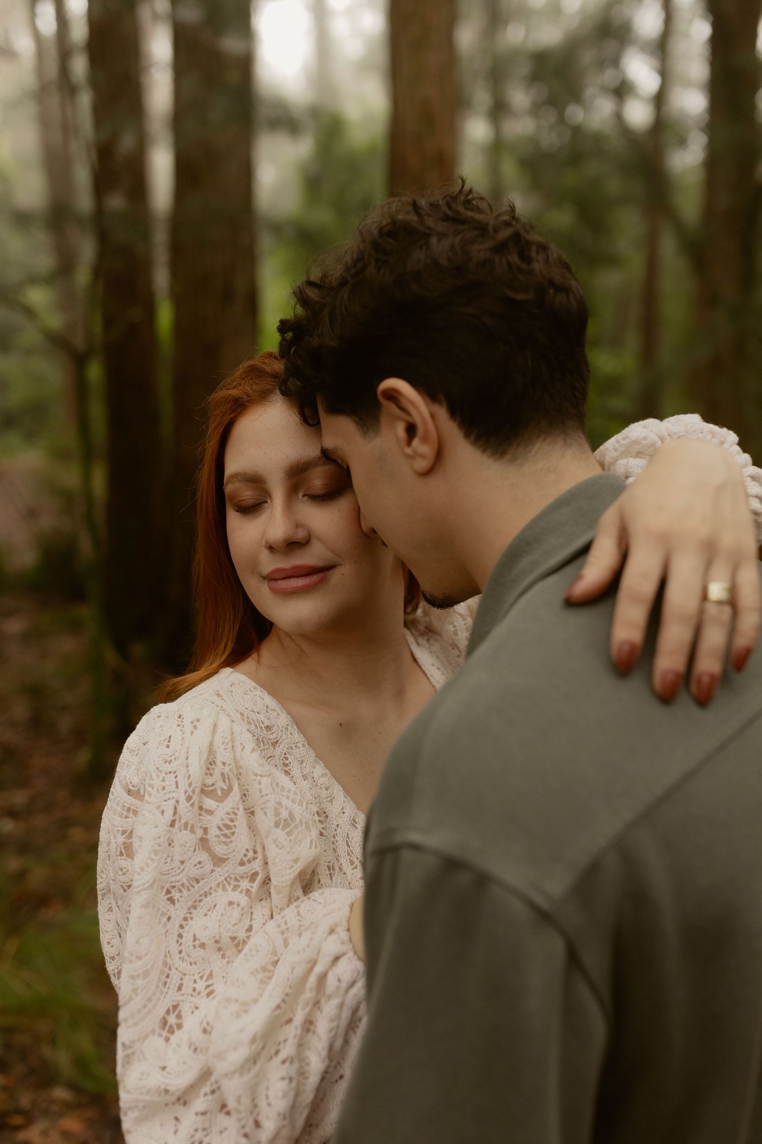 An intimate moment captured between two people embracing in a misty forest setting.