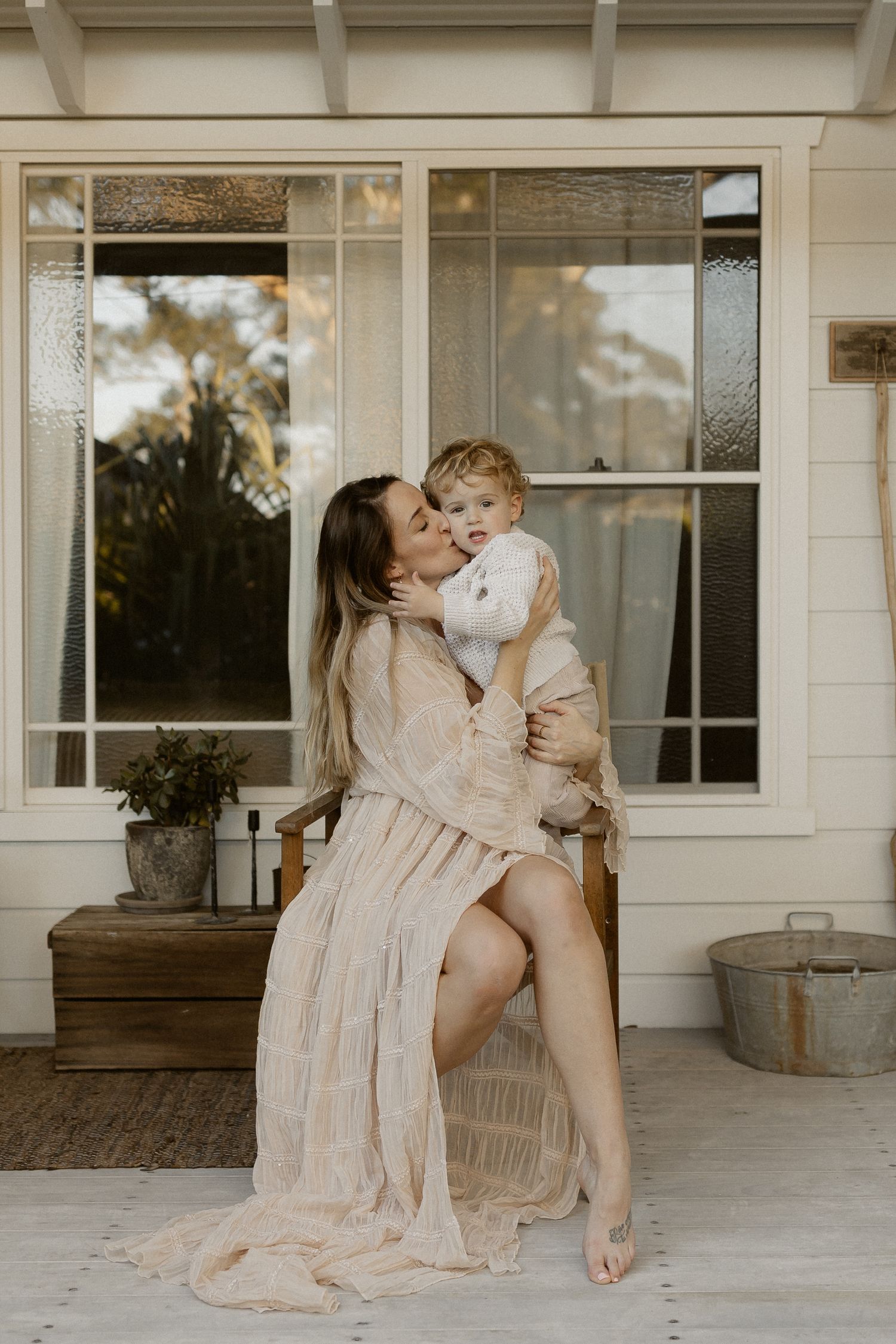 Sun-lit porch scene with light colored dresses and tender moments shared between two figures.