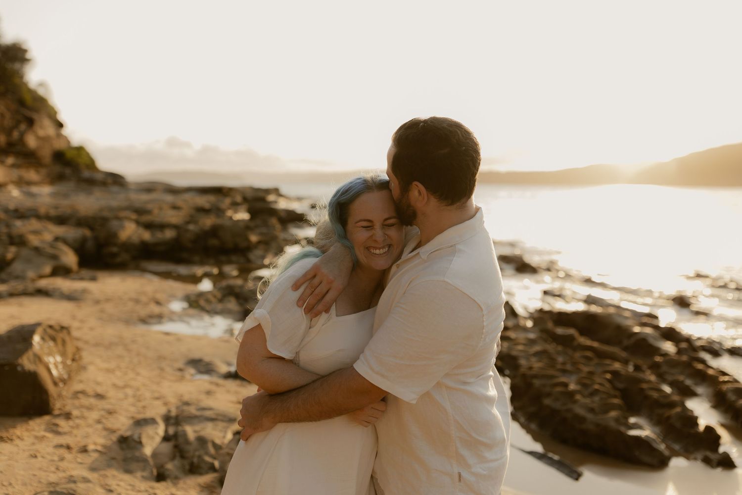Joyful embraces shared on a rocky coastline during golden hour.
