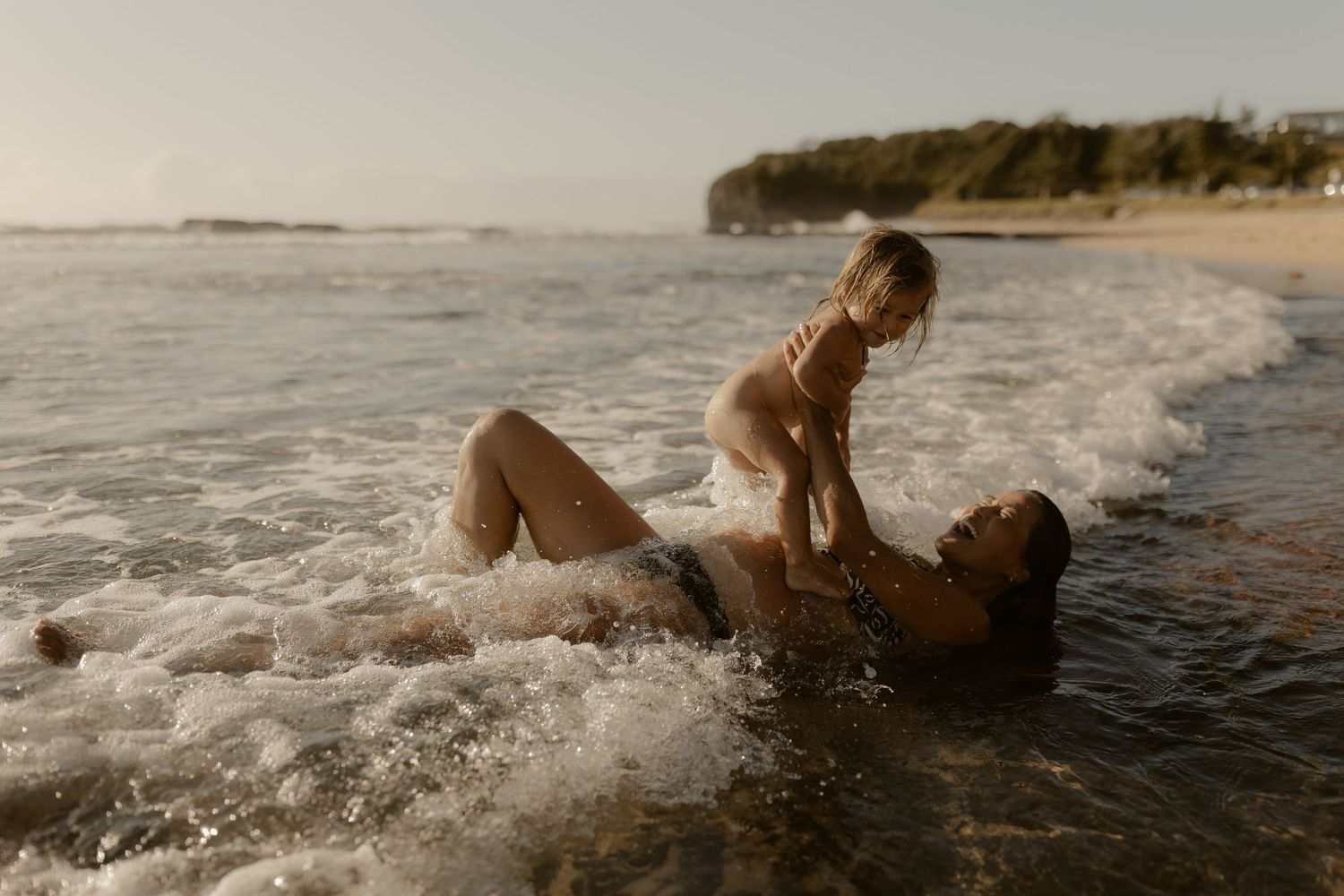 Waves crash around a couple enjoying a romantic moment in the ocean.