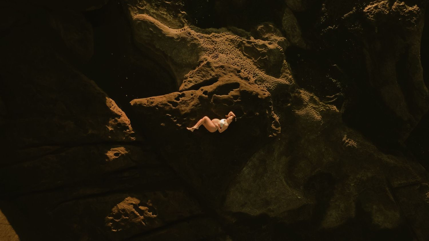 A dimly lit underwater cave interior with rocky formations and dark shadows creating a mysterious atmosphere.