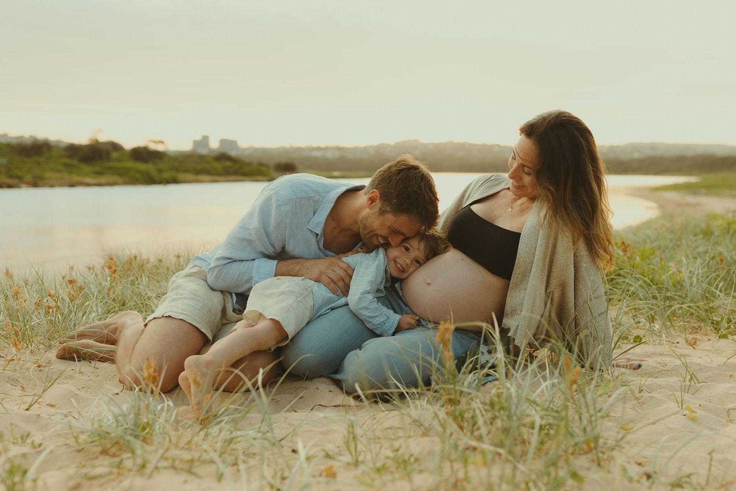 A couple lying together on sandy beach grass during a romantic moment.