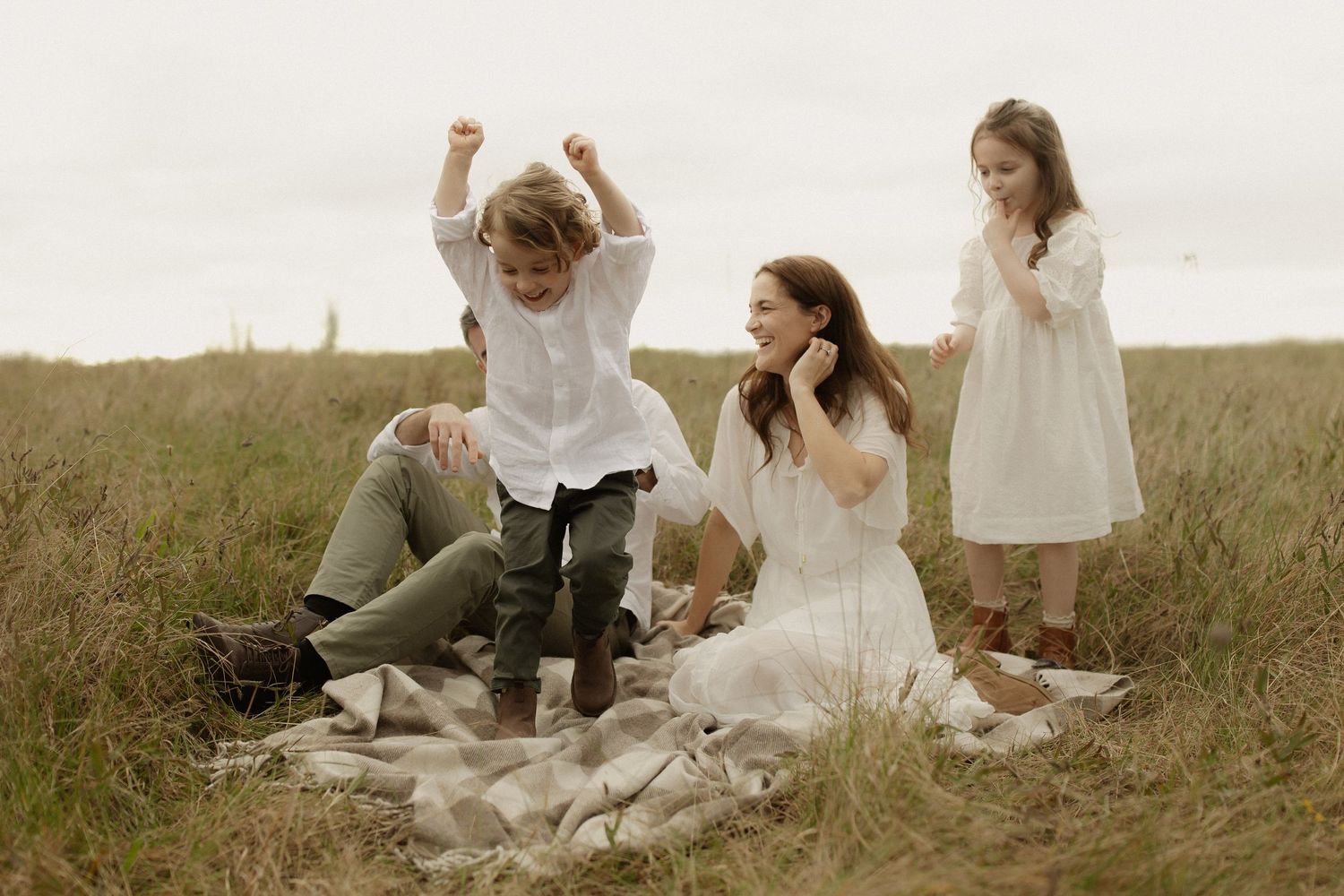 A group in white outfits sits together in a grassy meadow during a sunny outdoor gathering.