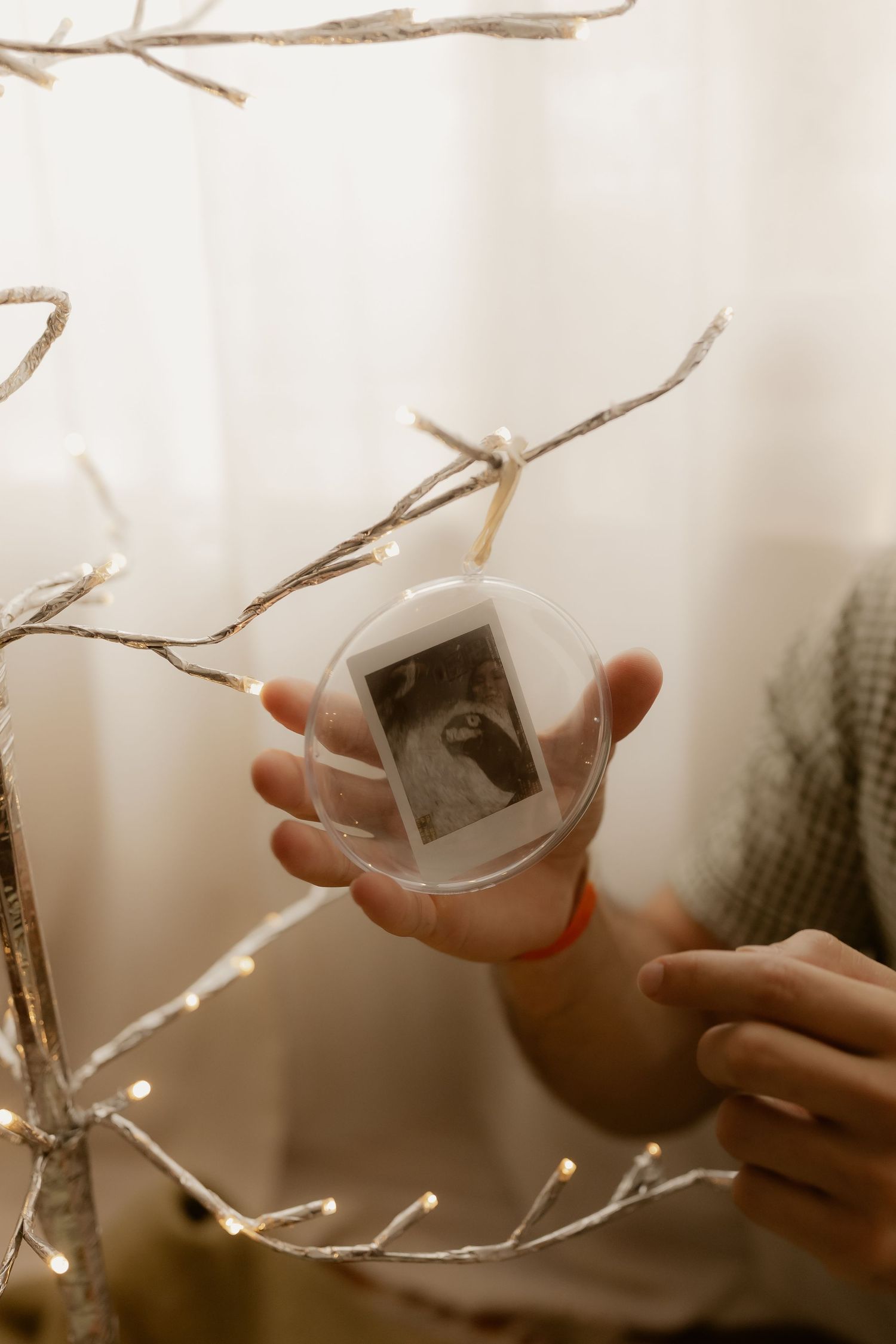 Hands holding ultrasound photos against bright window light.