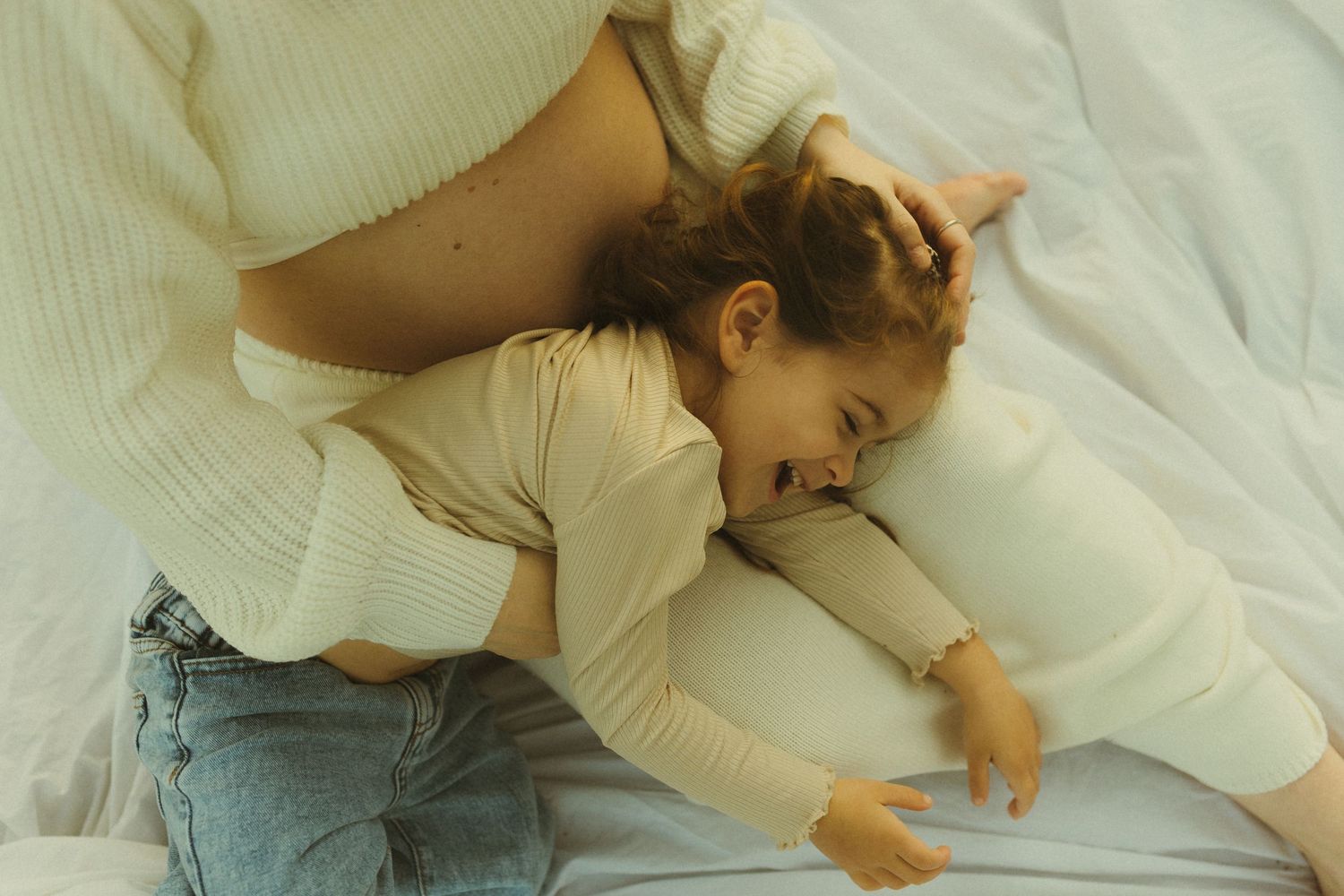Intimate candid moment showing gentle cuddles on soft white bedding.