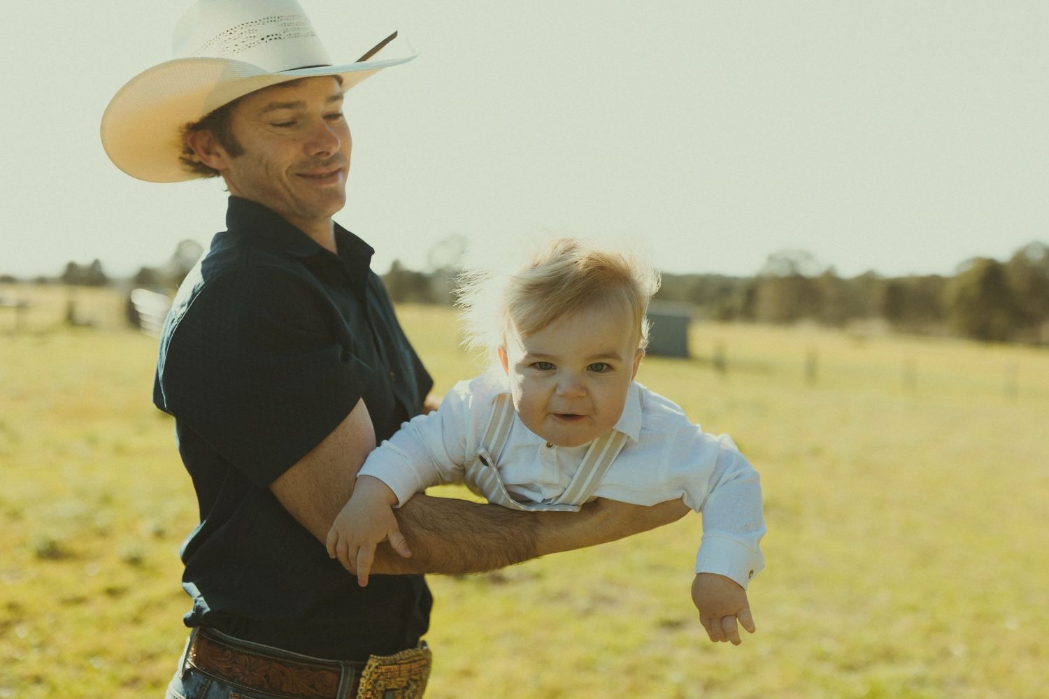 A joyful outdoor scene with people wearing cowboy hats playing in a sunlit field.