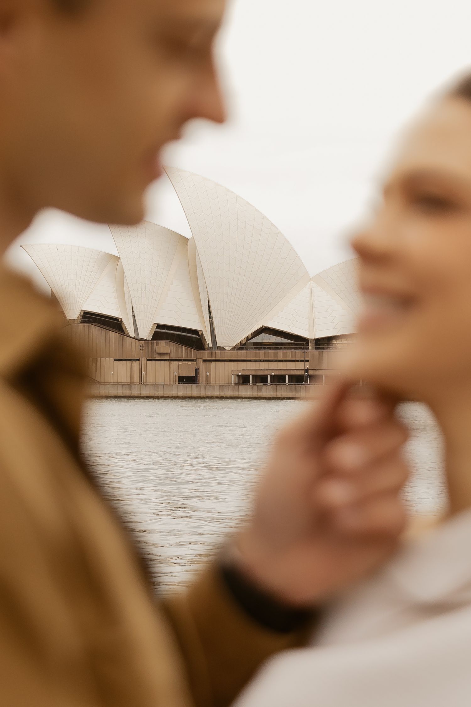Intimate couple moment with Sydney Opera House in soft focus.