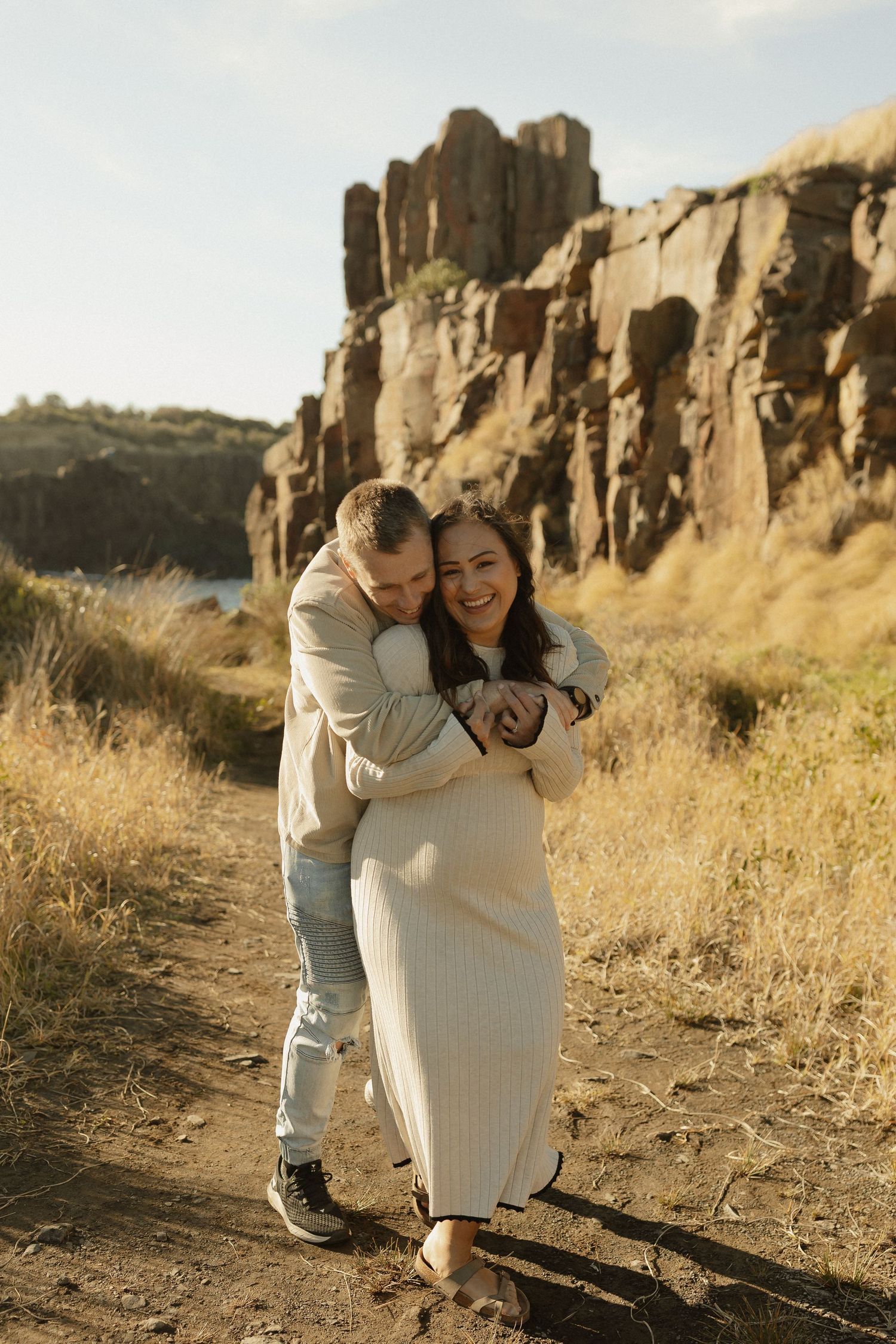 Family sharing intimate embraces against rocky cliffs in golden sunlight.